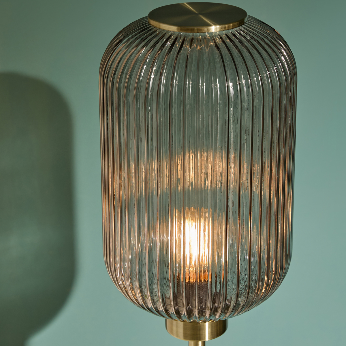 MADE.COM Briz floor lamp close up of tall ribbed grey glass shade lit with a warm bulb