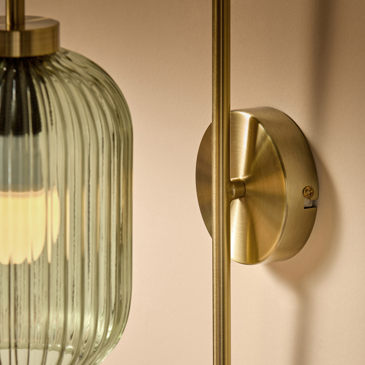 MADE.COM Briz wall light close up of ribbed green glass shade and brushed brass round backplate