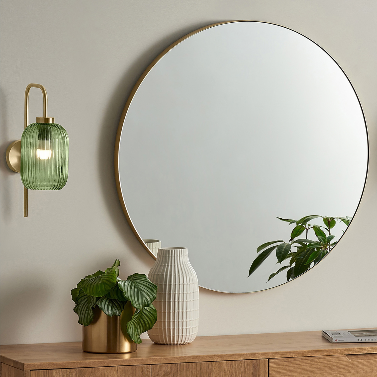 MADE.COM Briz wall light in brushed brass with ribbed green glass shade, lifestyle shot beside a round mirror
