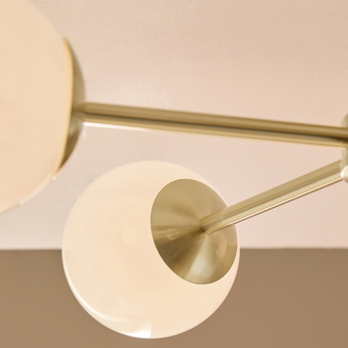 Close up of opal glass globe and brushed brass arm on MADE.COM Globe 5 light ceiling light