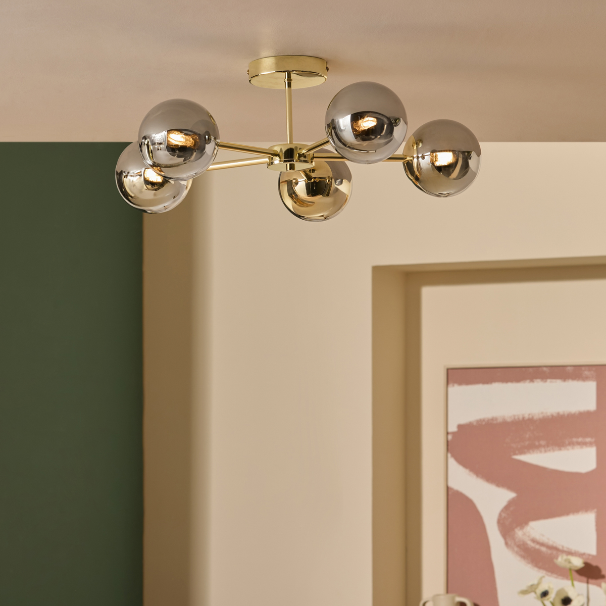 MADE.COM Globe 5 light flush ceiling light in brass with smoked glass globes above a grey sofa