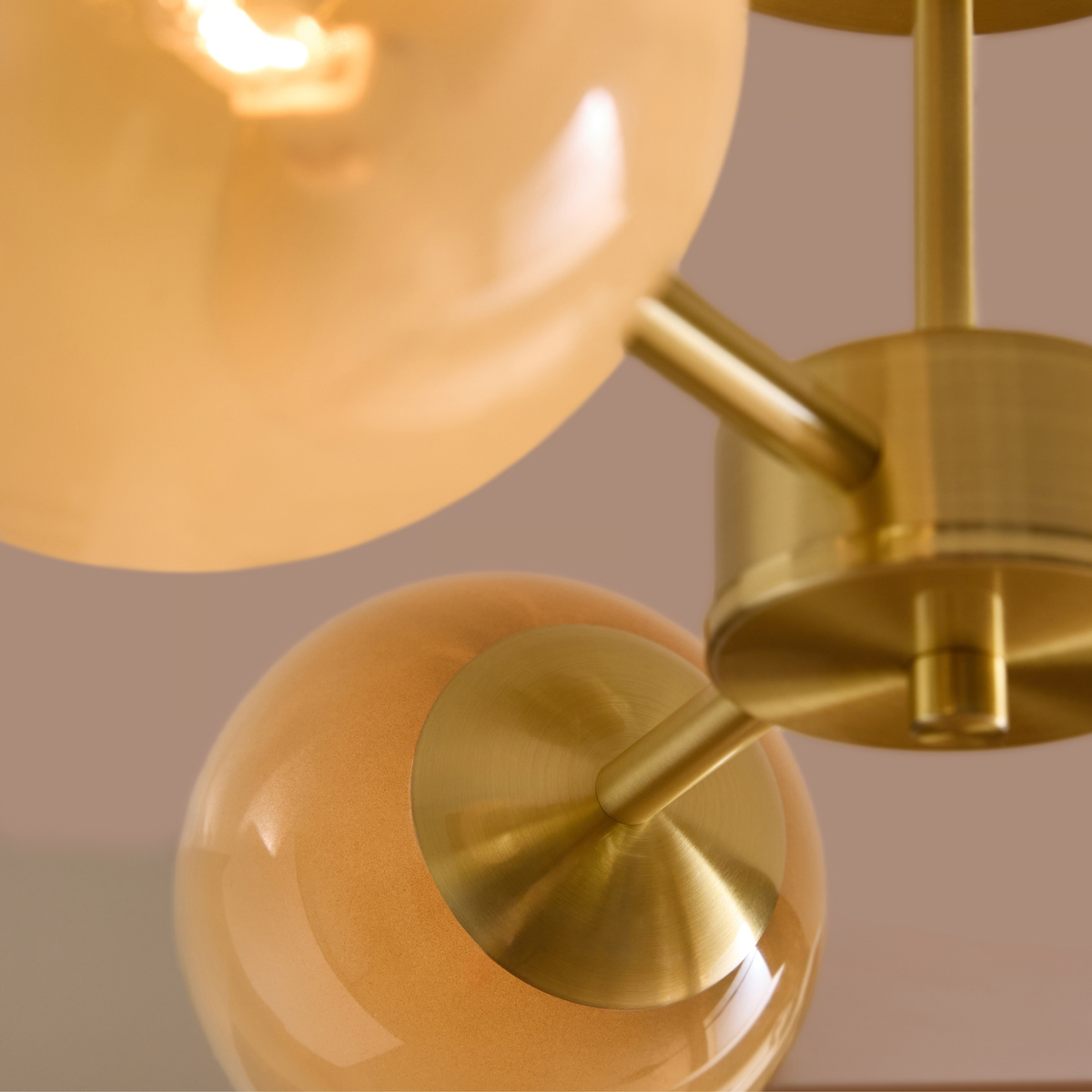 Detail of brass centre hub and warm amber glass globes on MADE Globe 3 light ceiling light