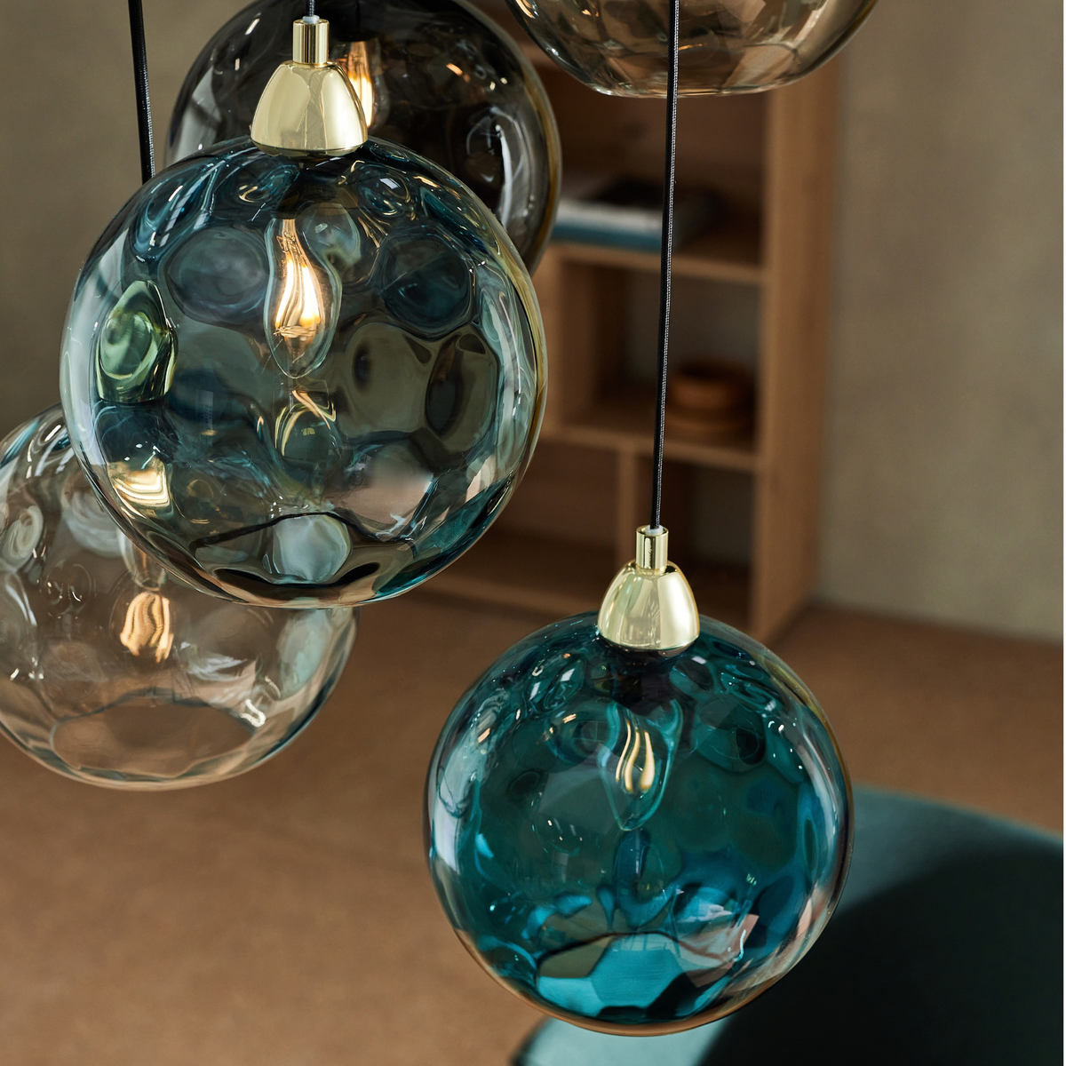 Close up of teal and smoky dimpled glass shades on MADE.COM Ilaria cluster pendant with brass caps