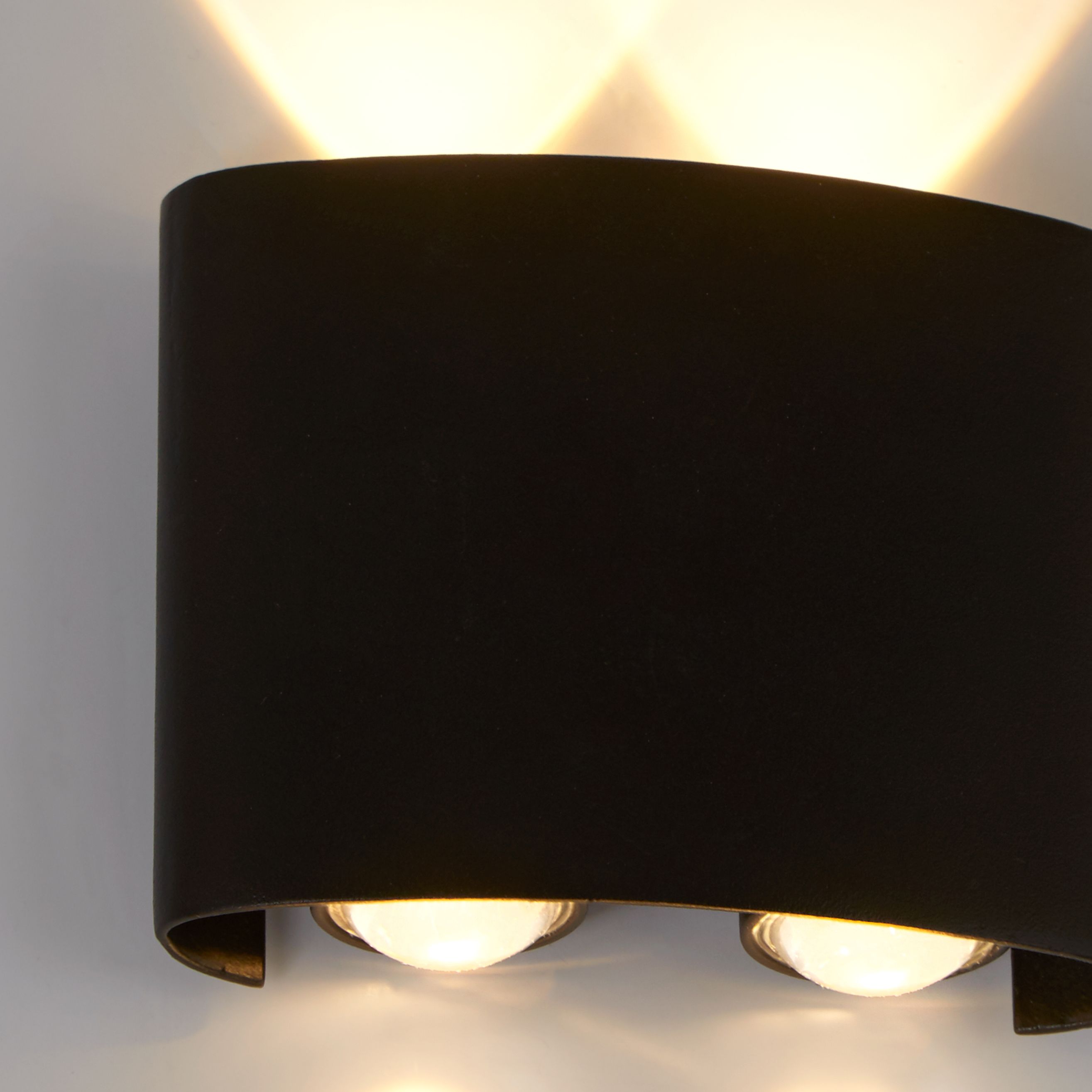 Close up of the Shadows LED outdoor wall light illuminated, showing warm white light spilling both up and down the wall from the two LED lens apertures