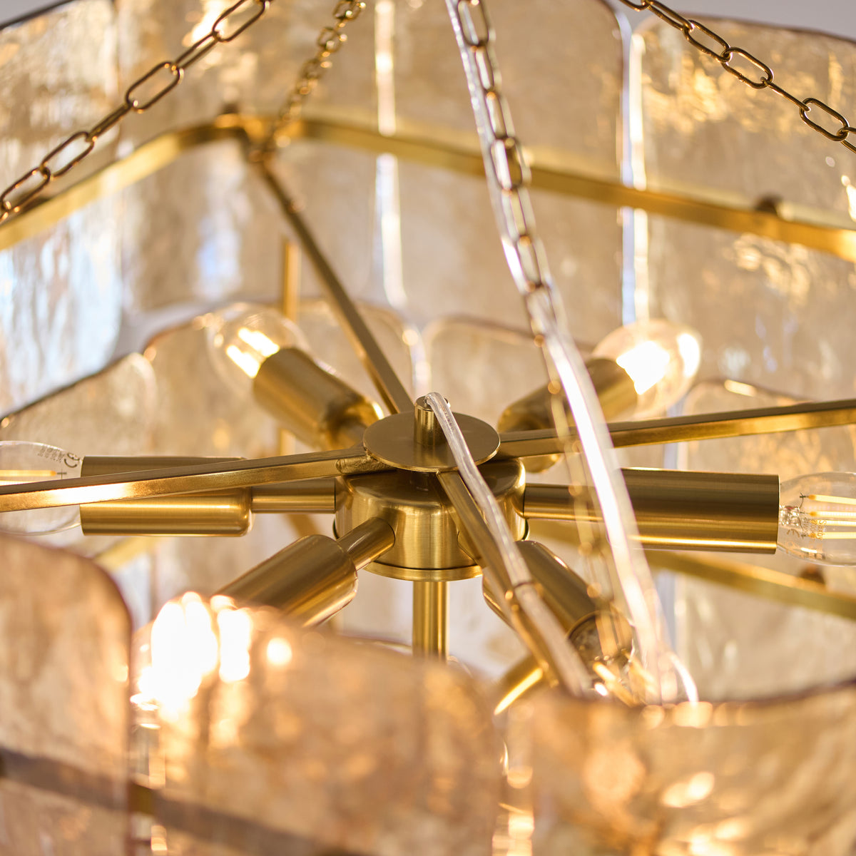 Extreme close up detail of the champagne handmade textured glass on the Endon Venice 10 light pendant showing the texture and brass fixing pins