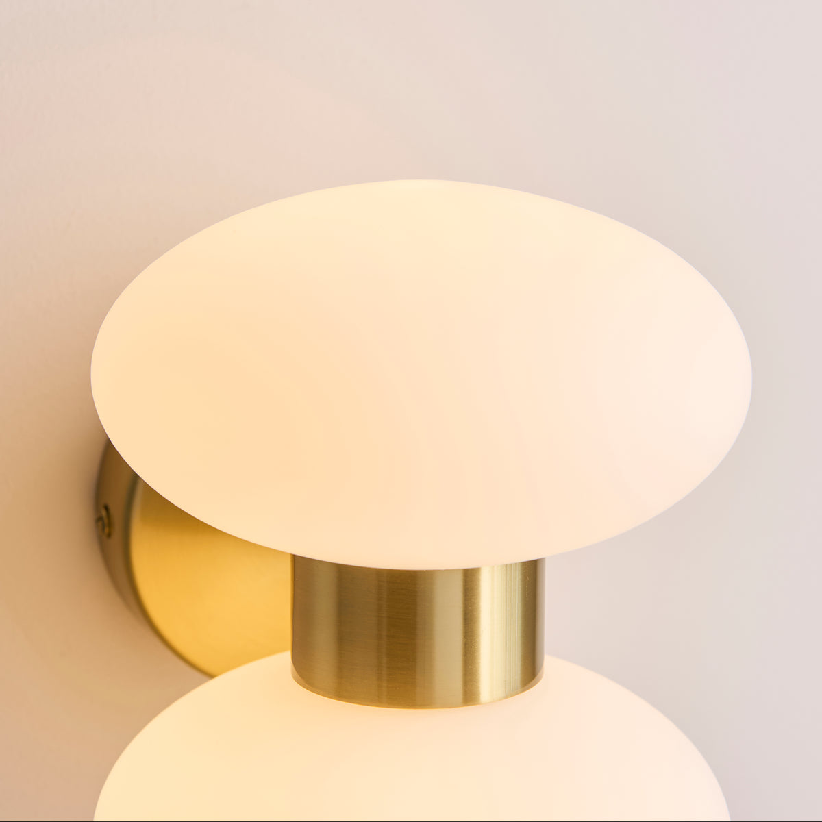 Close up detail shot of one opal glass globe shade on the Endon Rossano wall light showing the warm brass fitting