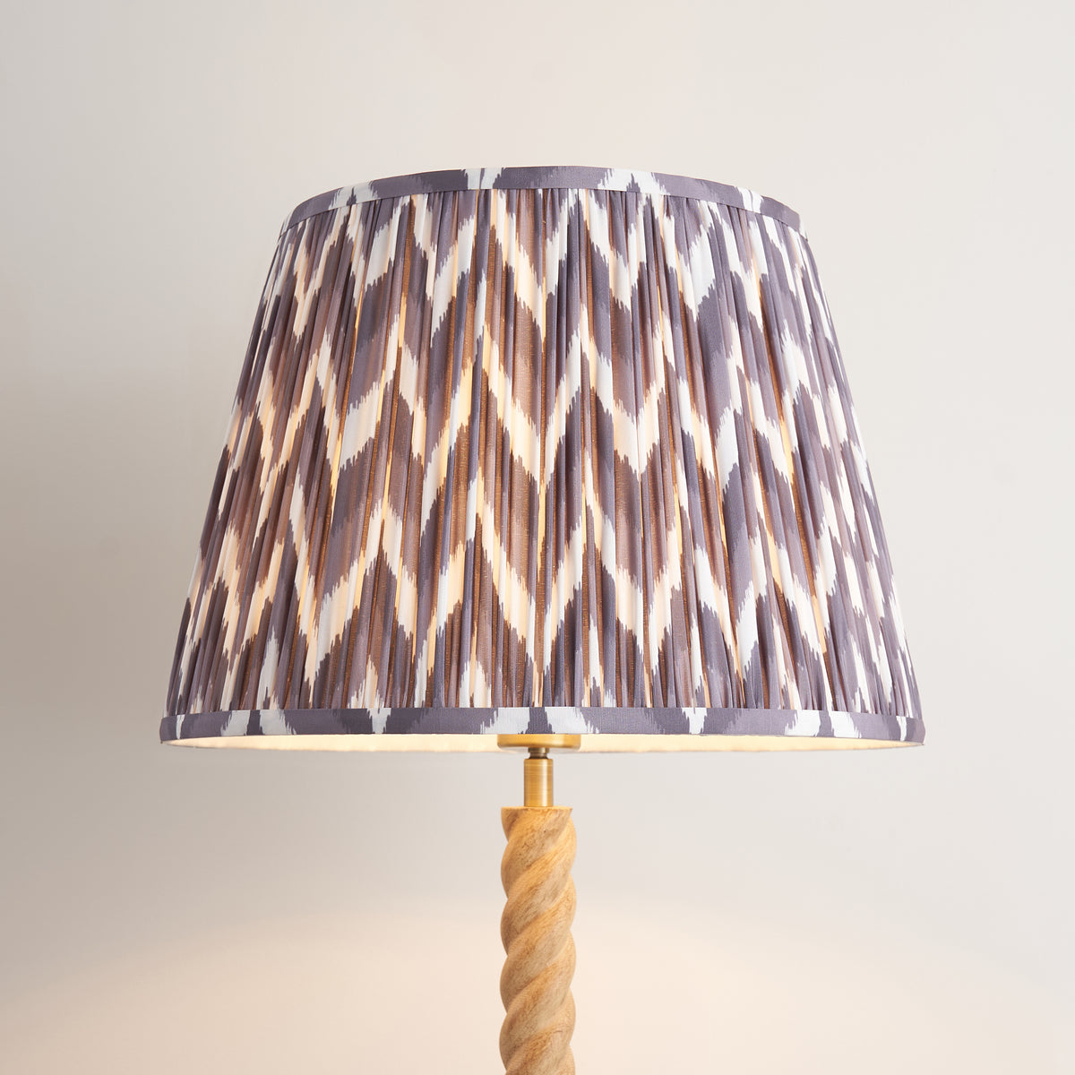 Close up of the lit pearl grey zigzag pleated shade on the Endon Twist floor lamp, showing the chevron print and twisted stem