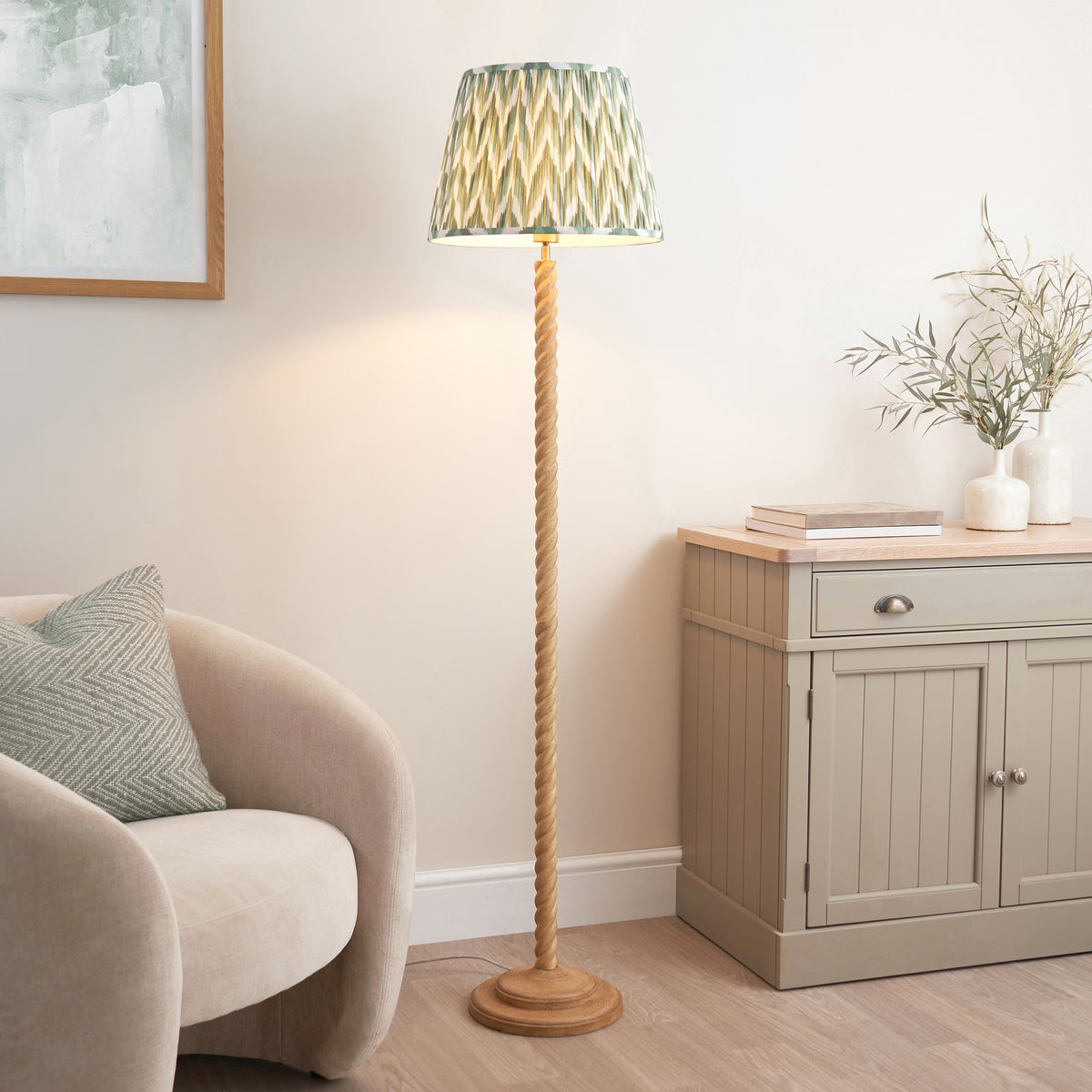 Endon Twist floor lamp in oak effect resin with green ZigZag shade lit in a living room beside a cream armchair and grey sideboard