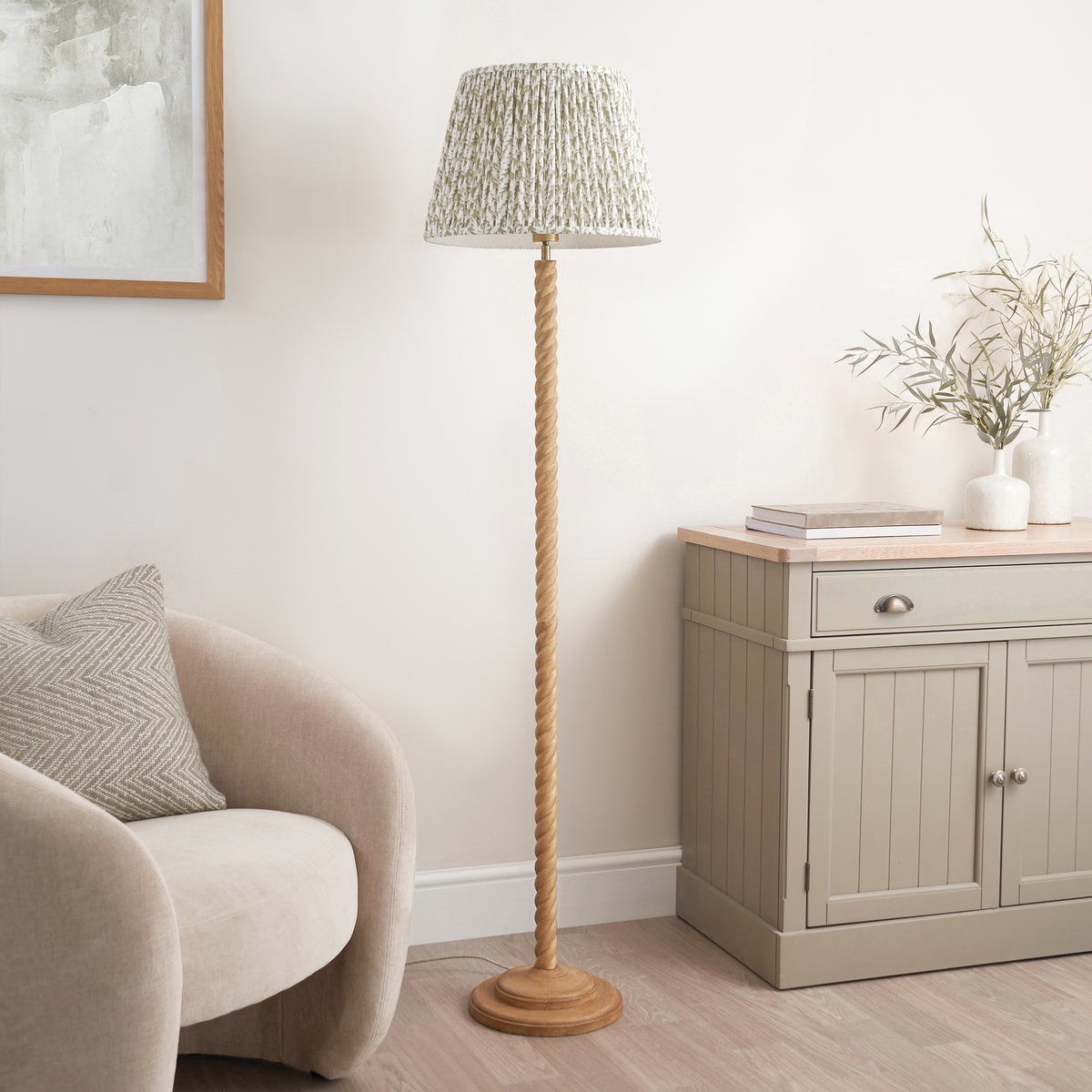 Endon Twist floor lamp unlit in a living room, oak effect twisted stem and sage green leaf print shade next to a sideboard with vases