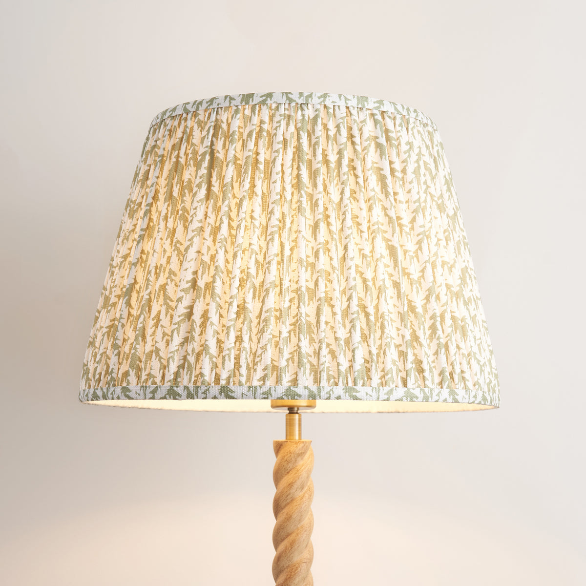 Close up of the lit herb garden green pleated Leaf shade on the Endon Twist floor lamp, with the leaf print and top of the stem