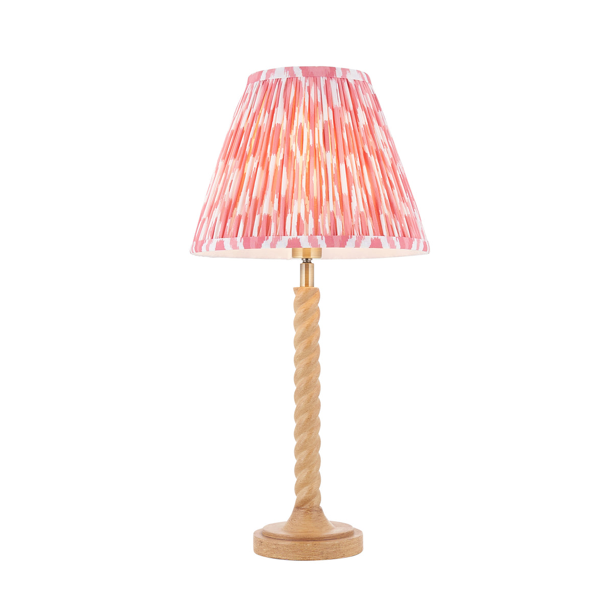 Endon Twist table lamp with oak effect twisted resin base and coral pink ikat shade, lit, cut out on a white background