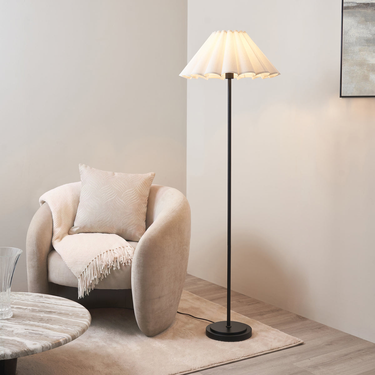 Endon Arlo and Ayla floor lamp lit in a living room beside a boucle armchair, marble side table and rug, matt black stem with vintage white scalloped shade