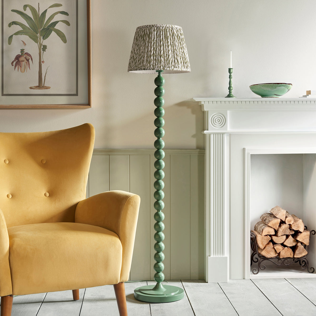 Endon Higgledy floor lamp unlit in a living room, gloss green sphere stem and leaf print shade next to a mustard armchair and white fireplace