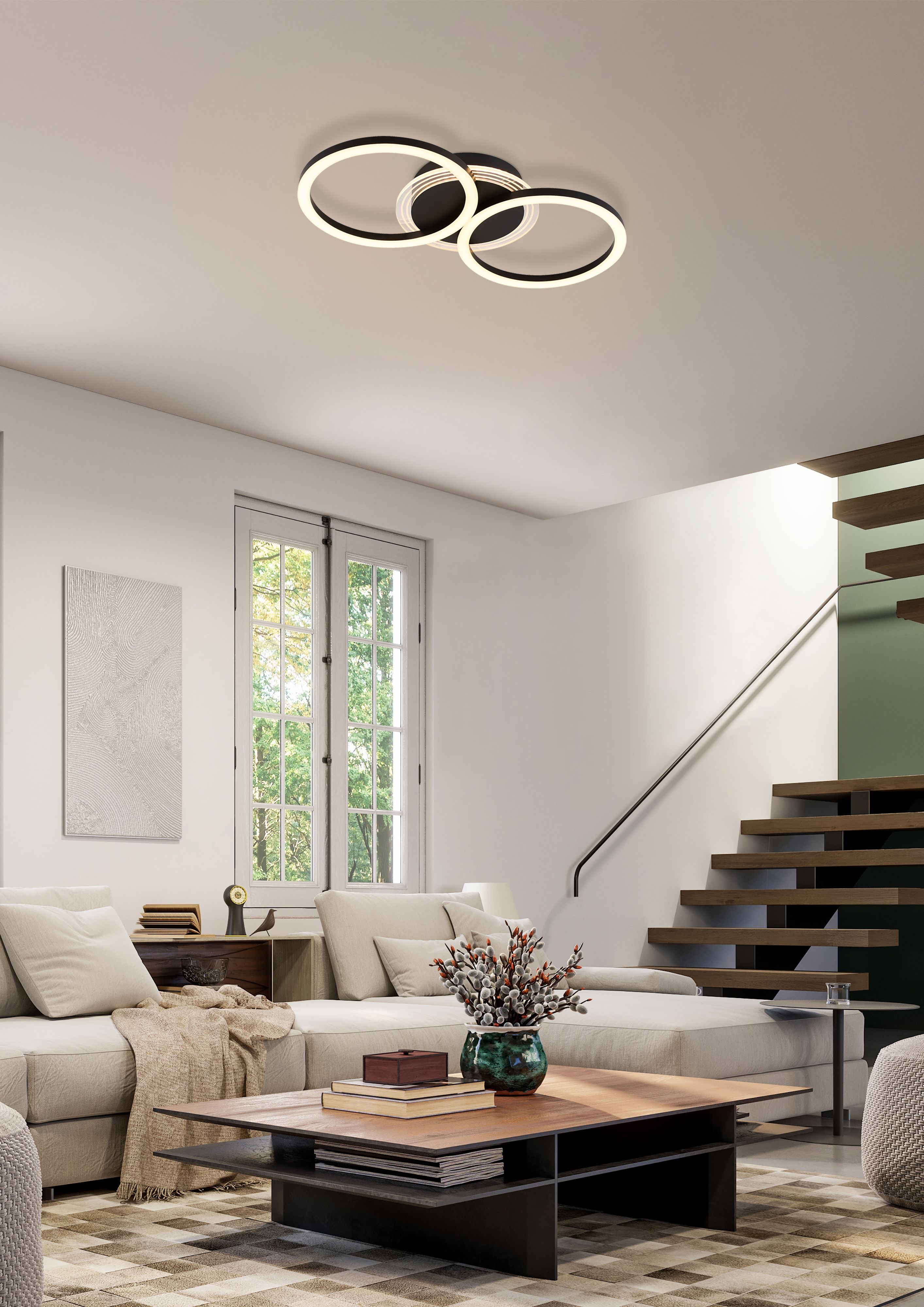 Contour double ring LED flush light in matt black installed in an open plan living room with a staircase