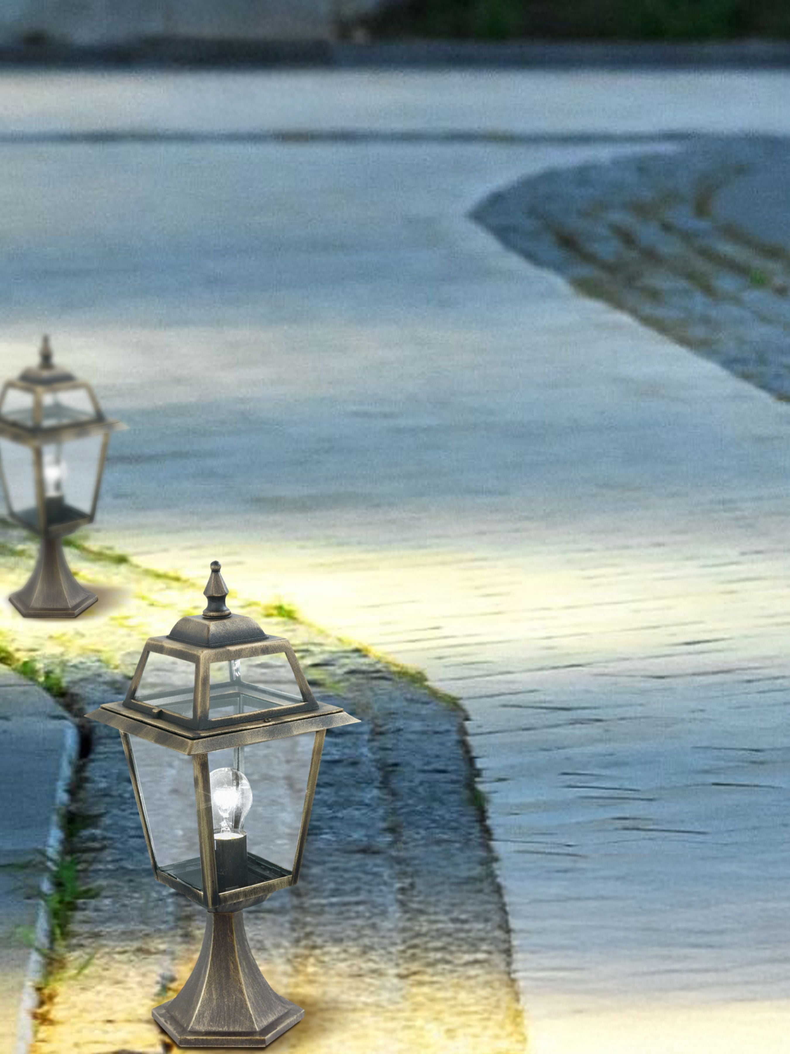 Two New Orleans outdoor post lights lit along a garden path at dusk