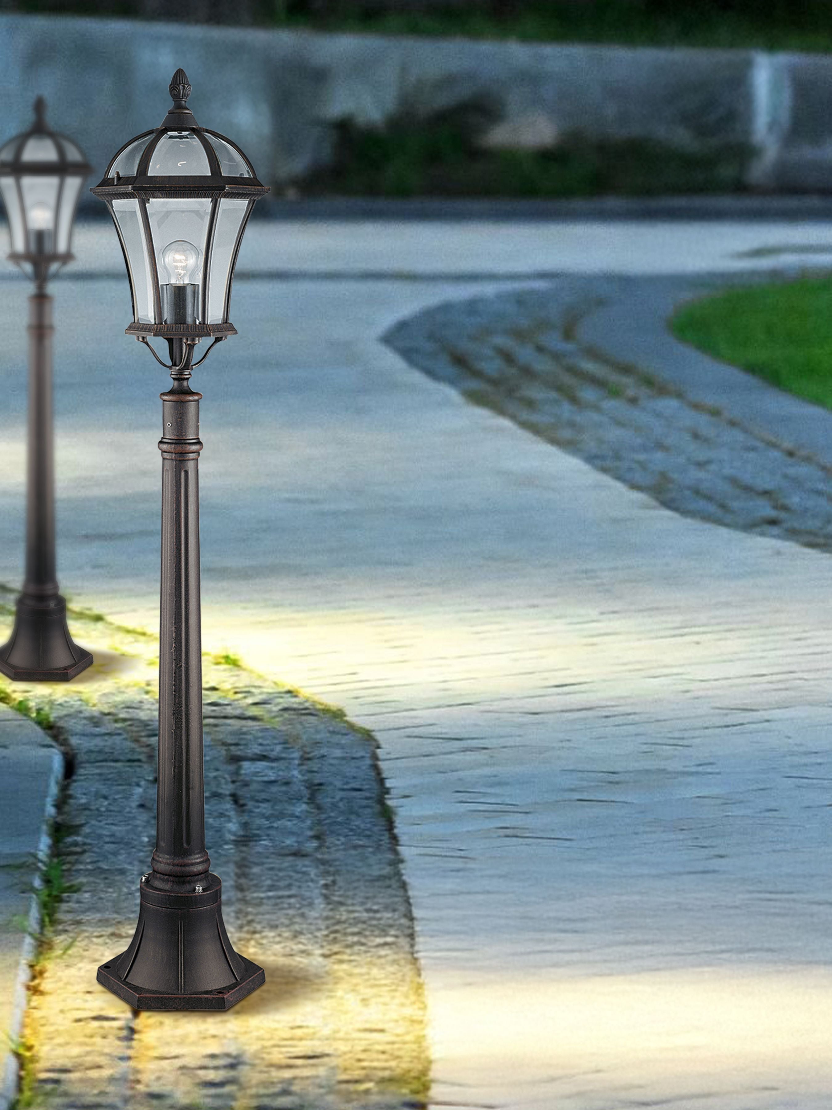 Capri Outdoor Post lit at dusk on a paved garden path, with a matching post visible further along the path