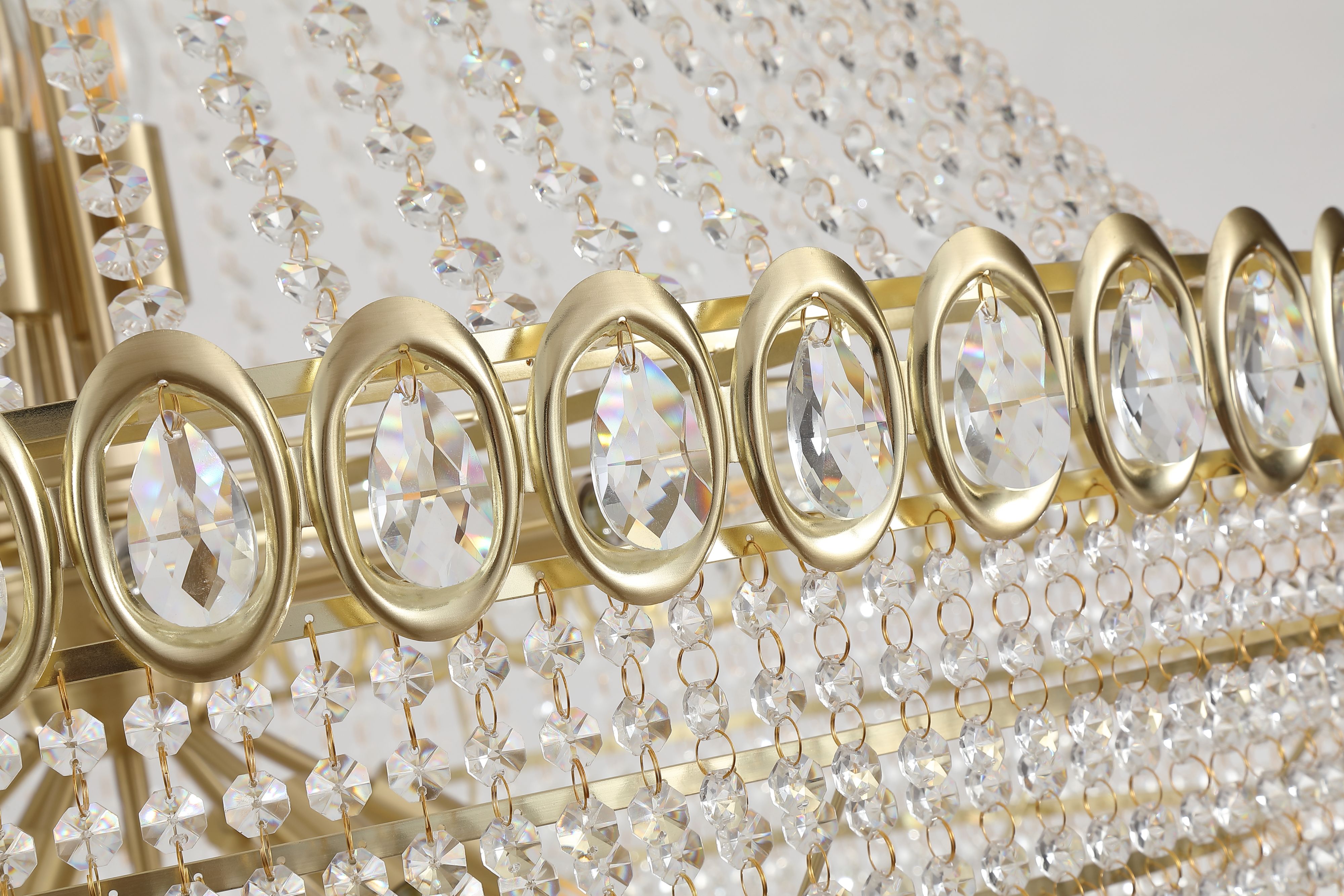 Close up of the oval faceted crystal jewels set into the satin brass band at the rim of the Louis Phillipe chandelier