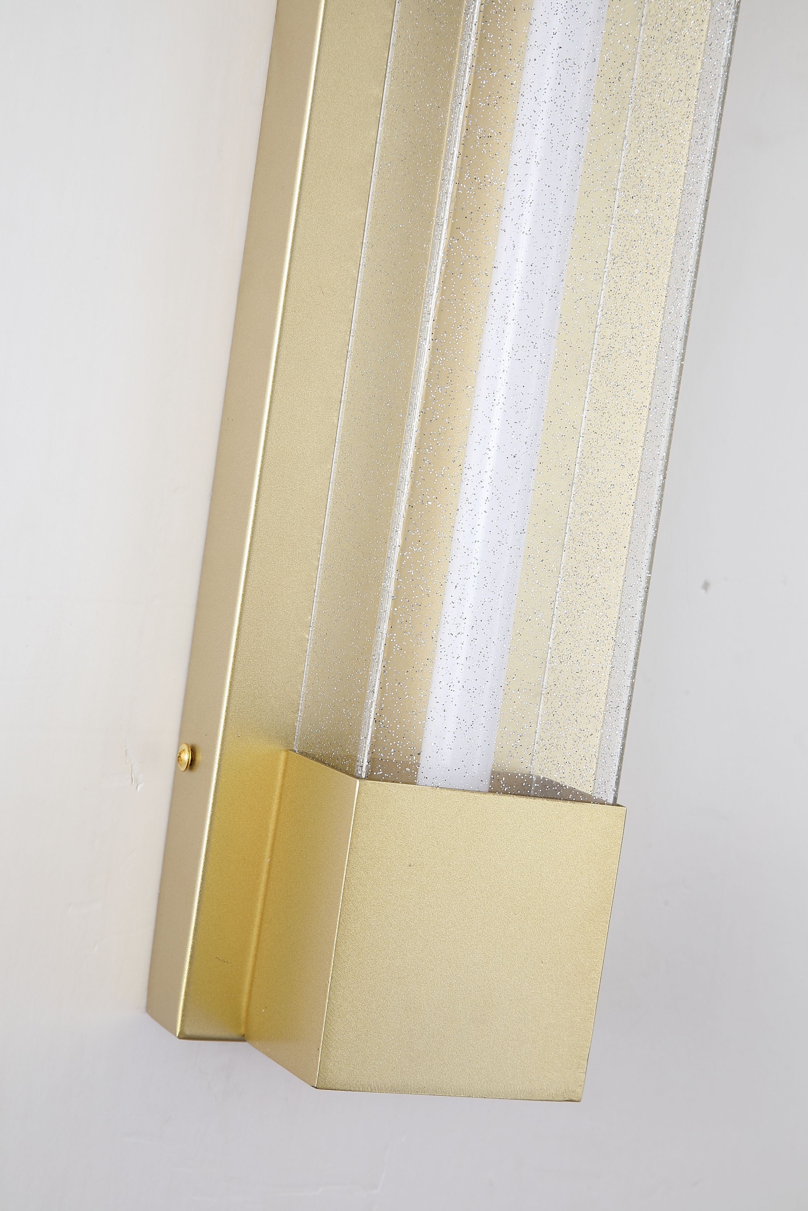 Close up angled detail of the Sacramento outdoor wall light in painted gold showing the acrylic light strip and textured finish, mounted on a wall