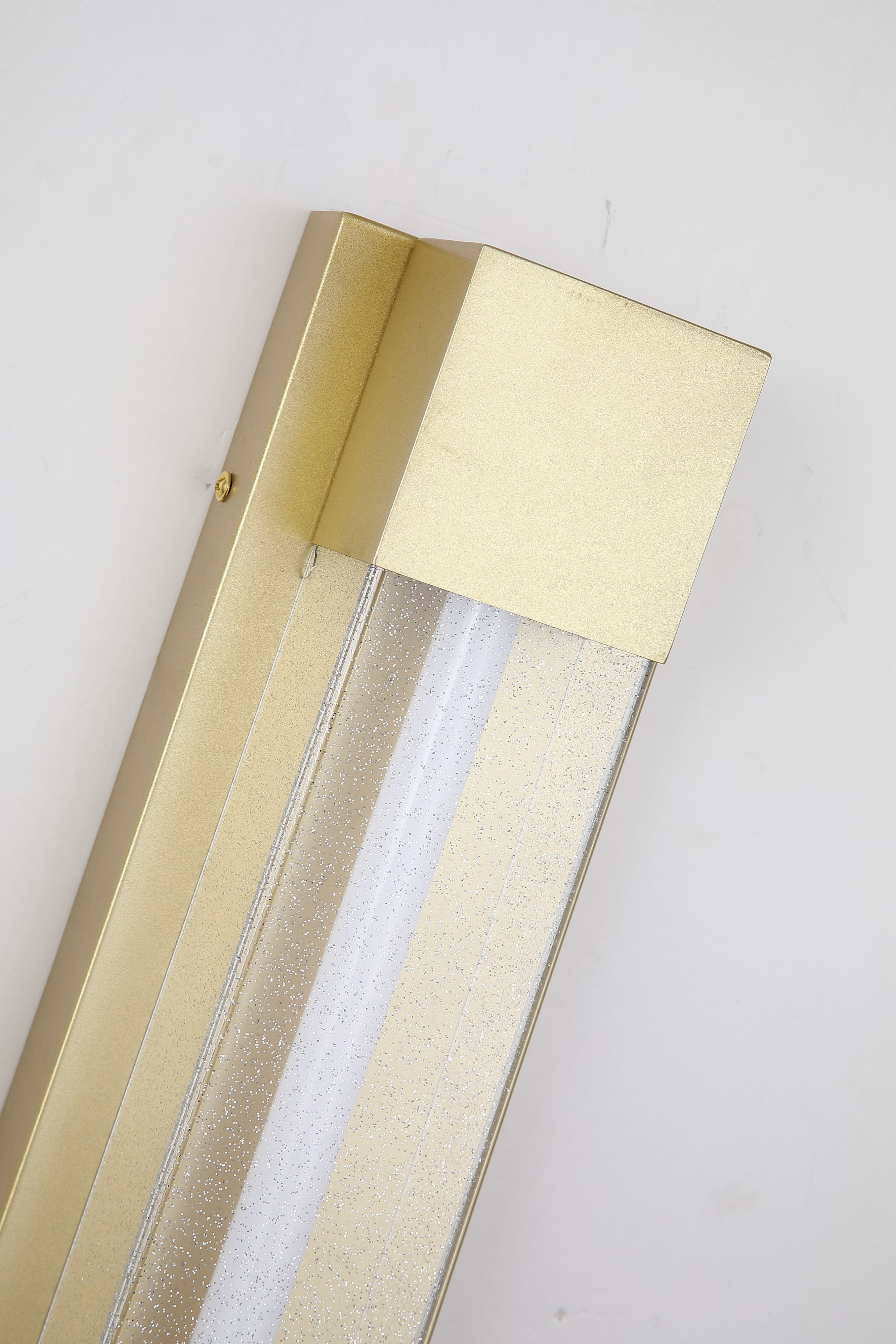 Close up angled detail of the Sacramento 60cm outdoor wall light in painted gold showing the acrylic light strip and textured finish, mounted on a wall