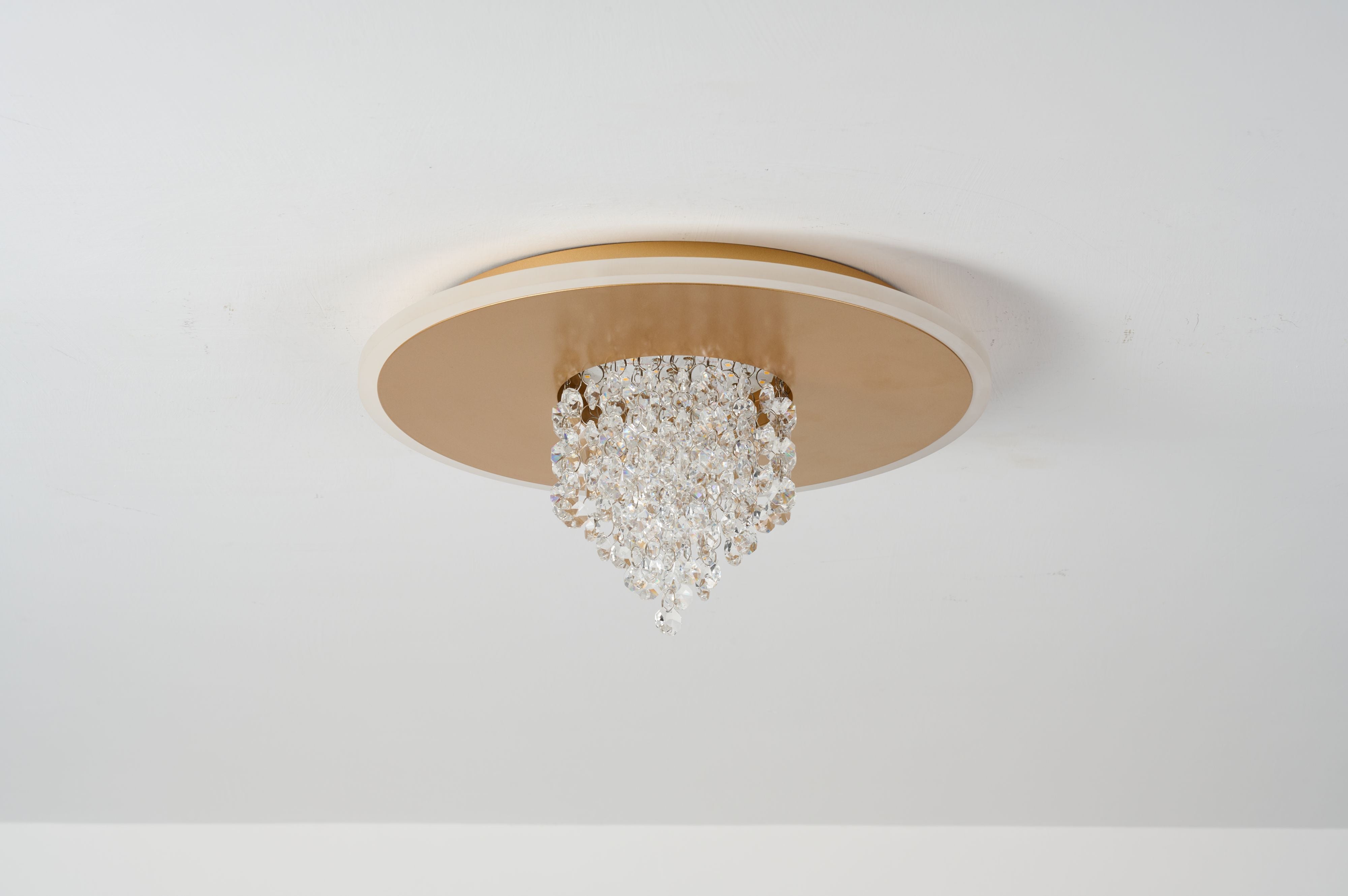 Searchlight Deluge LED flush ceiling light in gold mounted on a white ceiling, three quarter view showing the crystal cascade