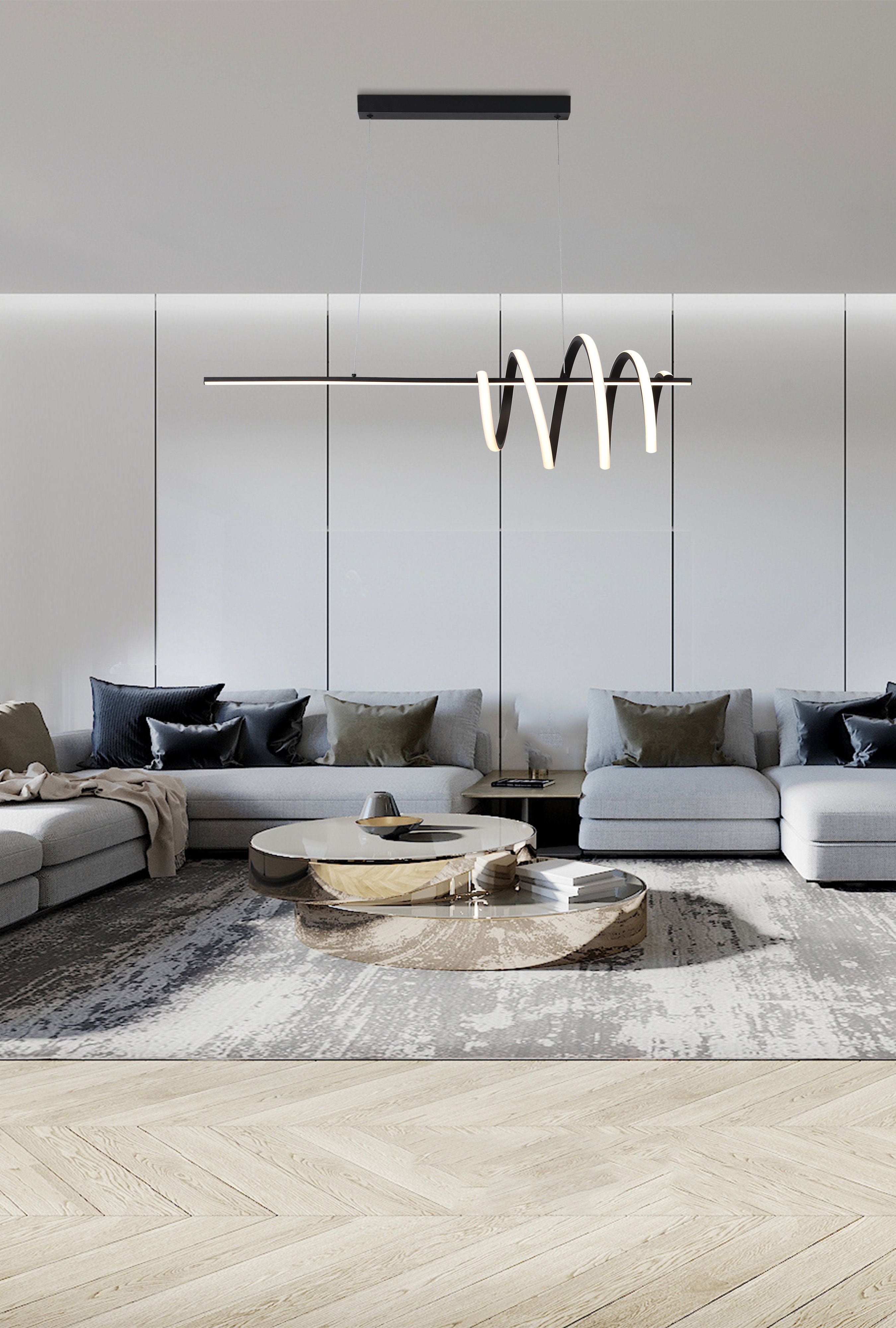 Sword LED Pendant in black styled above a grey sectional sofa and round mirrored coffee table in a modern living room