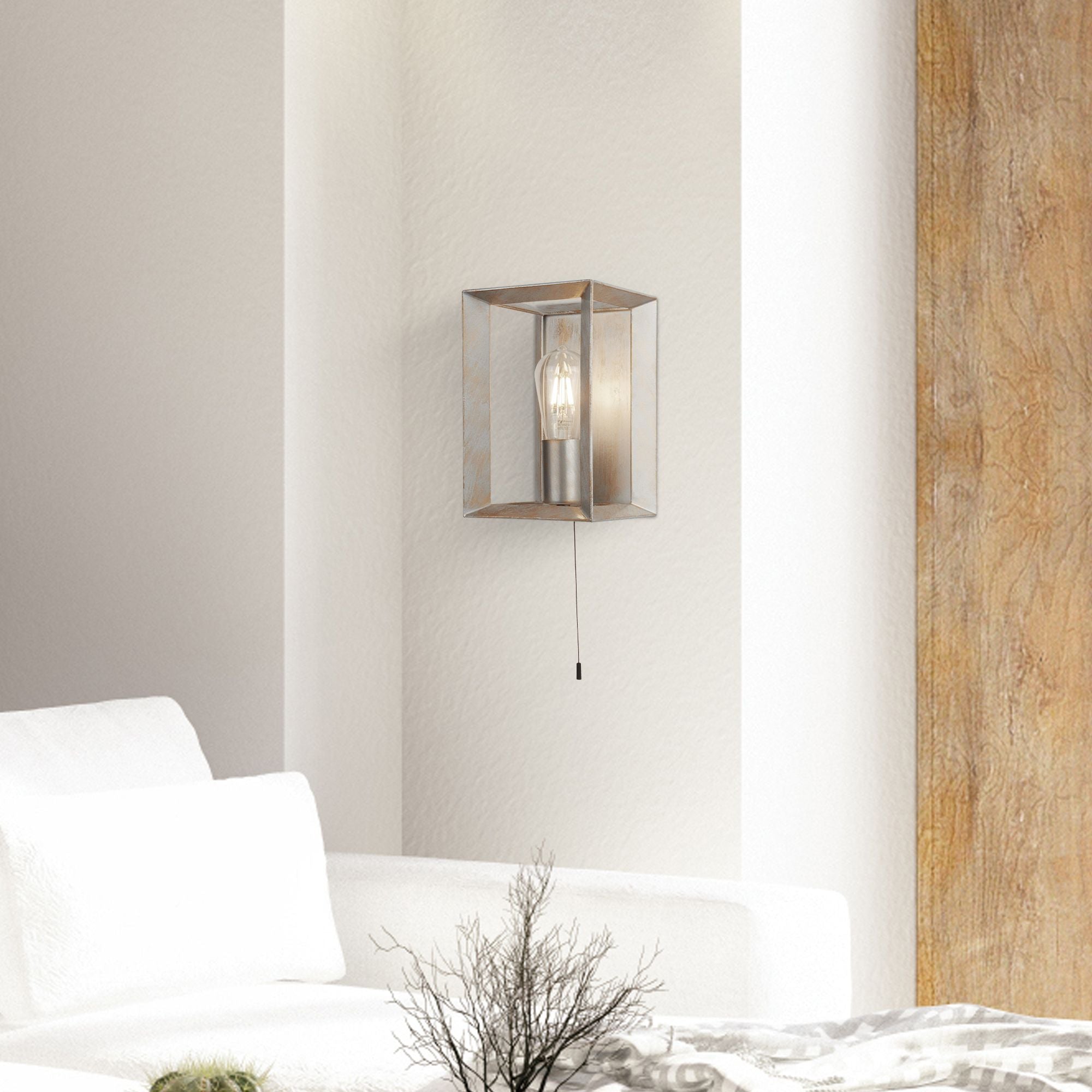Searchlight Heaton Wall Light styled on a plain wall beside a white sofa and dried branch, with the pull cord switch visible below the fitting