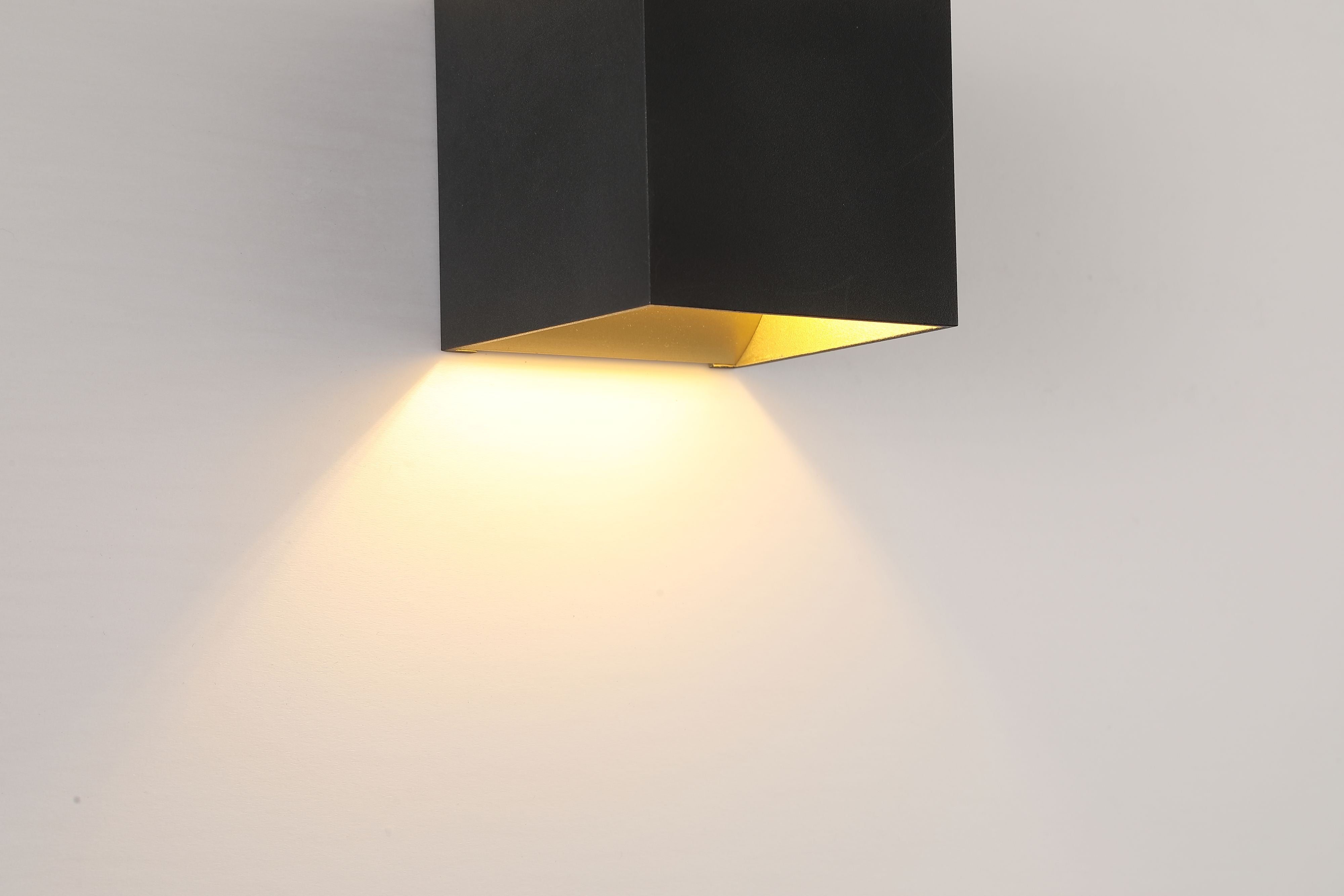 Close up of the Searchlight Newton wall light showing the gold toned interior of the bottom light channel and warm glow