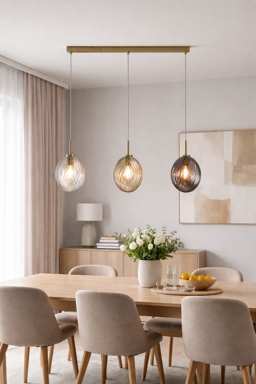 Searchlight Whirl 3 light bar pendant with clear, champagne and smoked glass shades hung above a round dining table with wishbone style chairs, in a light room with sheer curtains and framed artwork