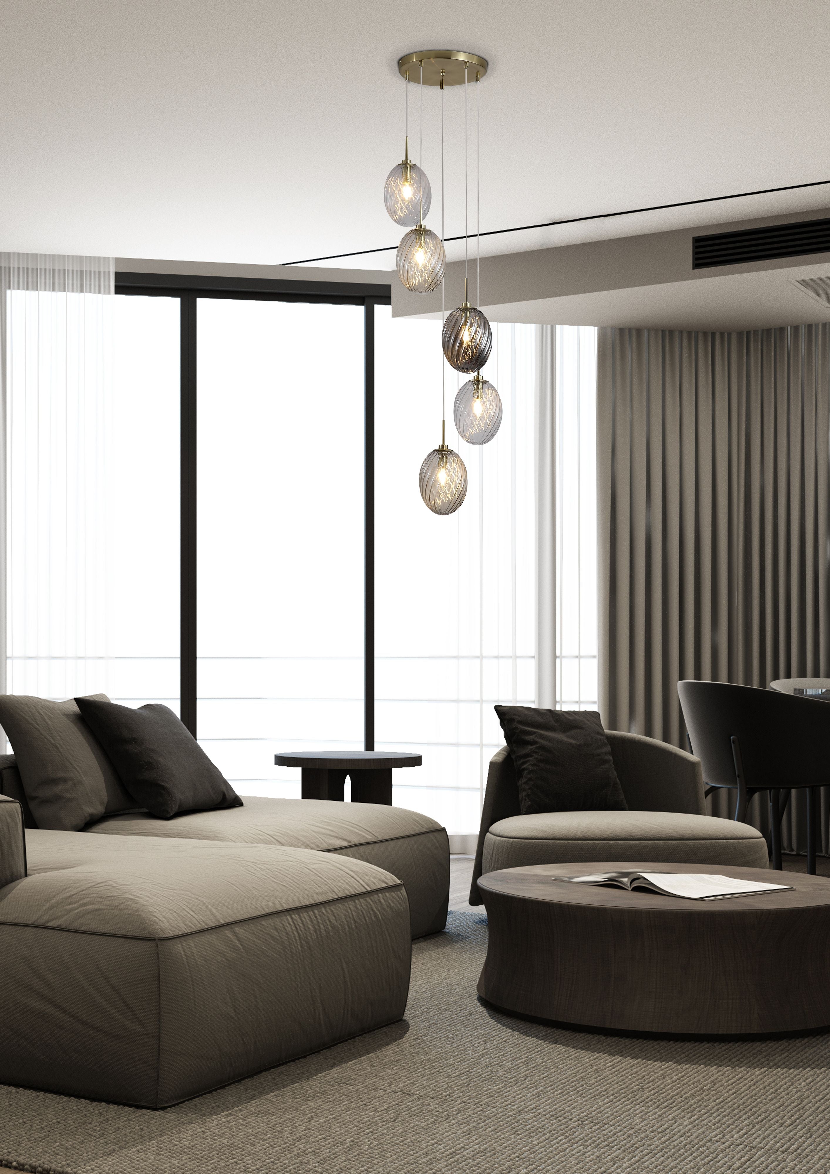 Searchlight Whirl 5 light multi drop pendant with clear, champagne and smoked glass shades hung above a seating area with dark upholstered furniture and floor to ceiling curtained windows