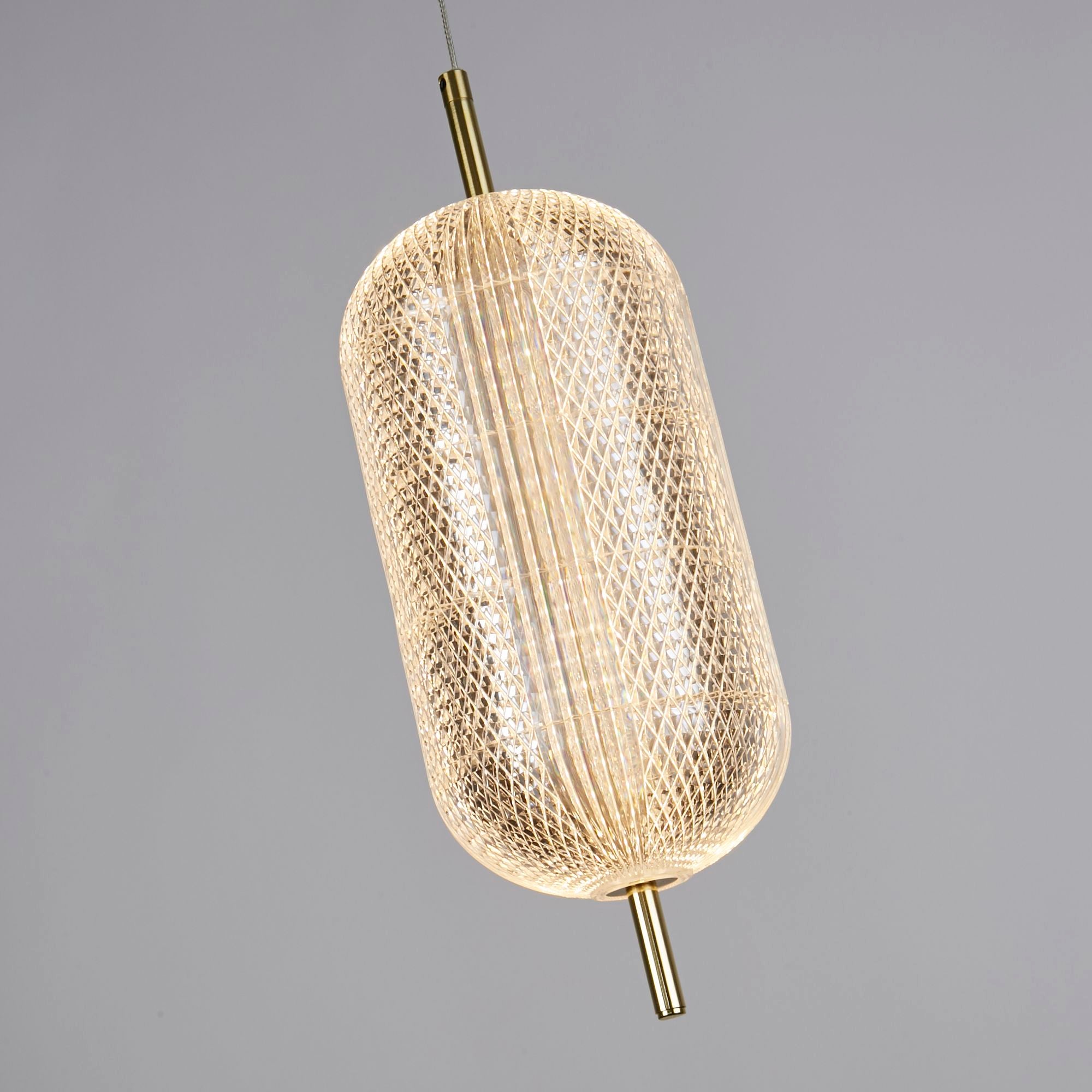 Close up angled view of the Capsule pendant's faceted acrylic lattice shade in satin brass, showing the diamond textured pattern lit from within