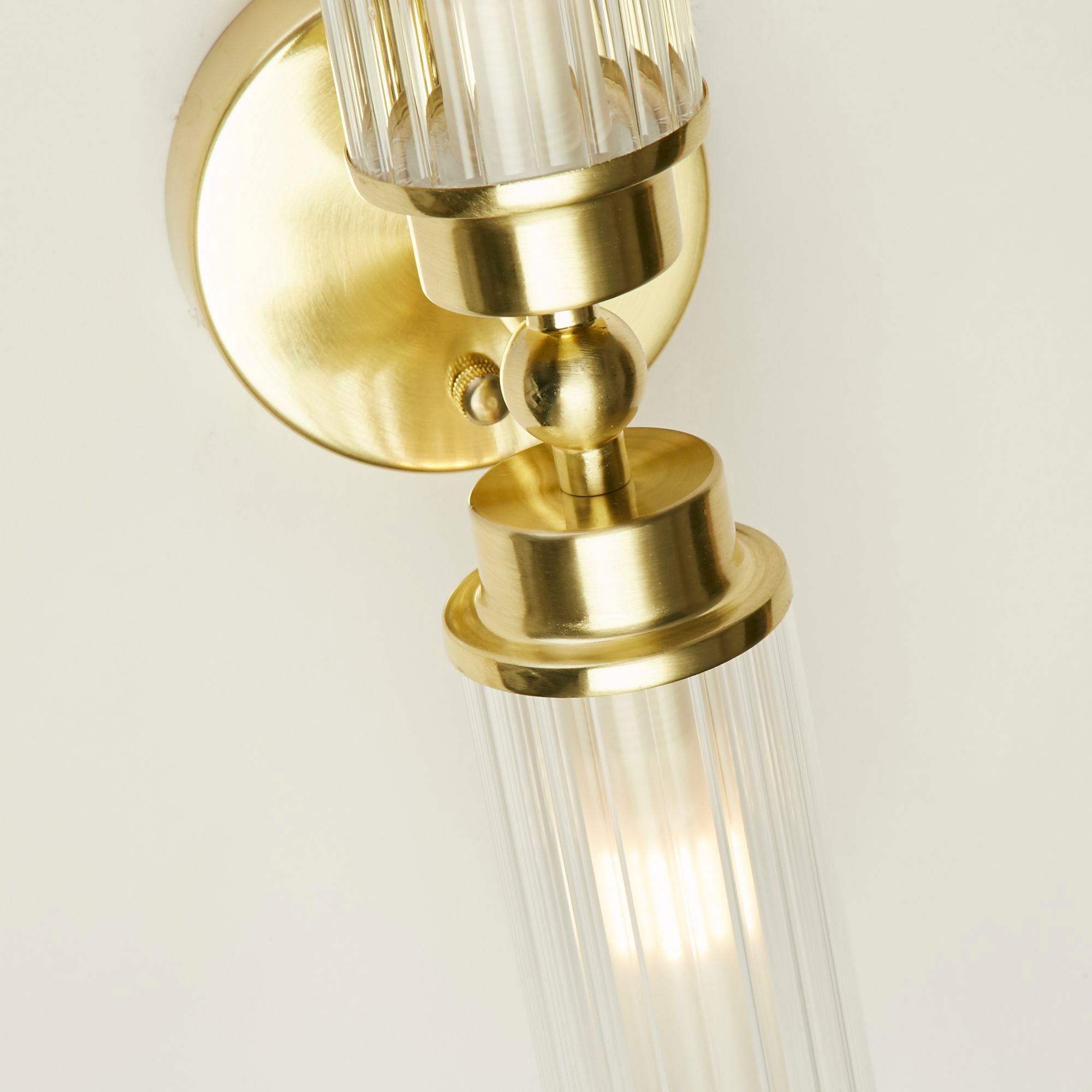 Close up of the satin brass ball joint and mounting bracket on the Searchlight Imperial 2 Light Wall Light, showing the fluted glass detail