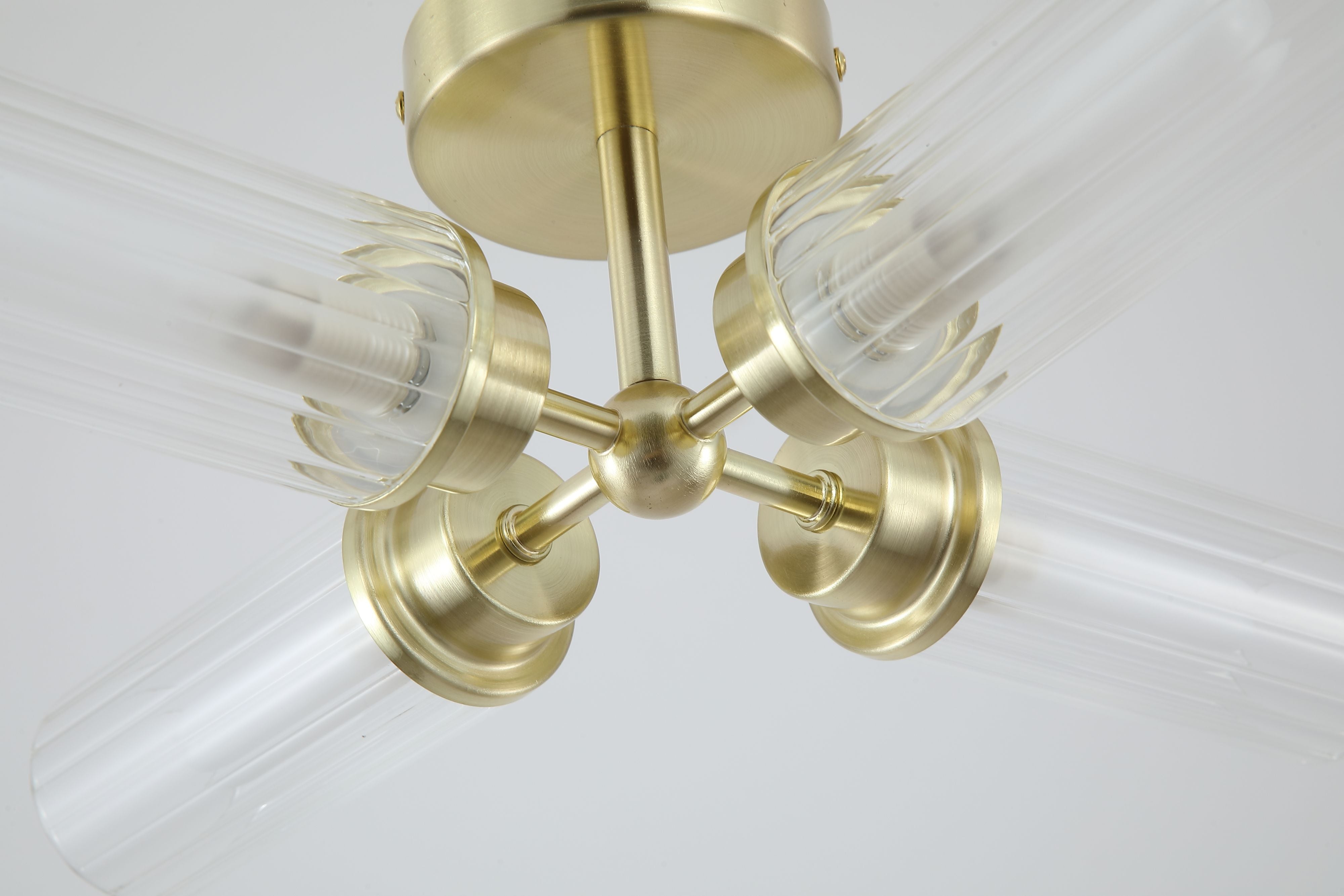 Close up of one ribbed glass shade on the Searchlight Imperial 4 Light Flush in satin brass, showing the fluted texture and warm glow of the lit bulbs