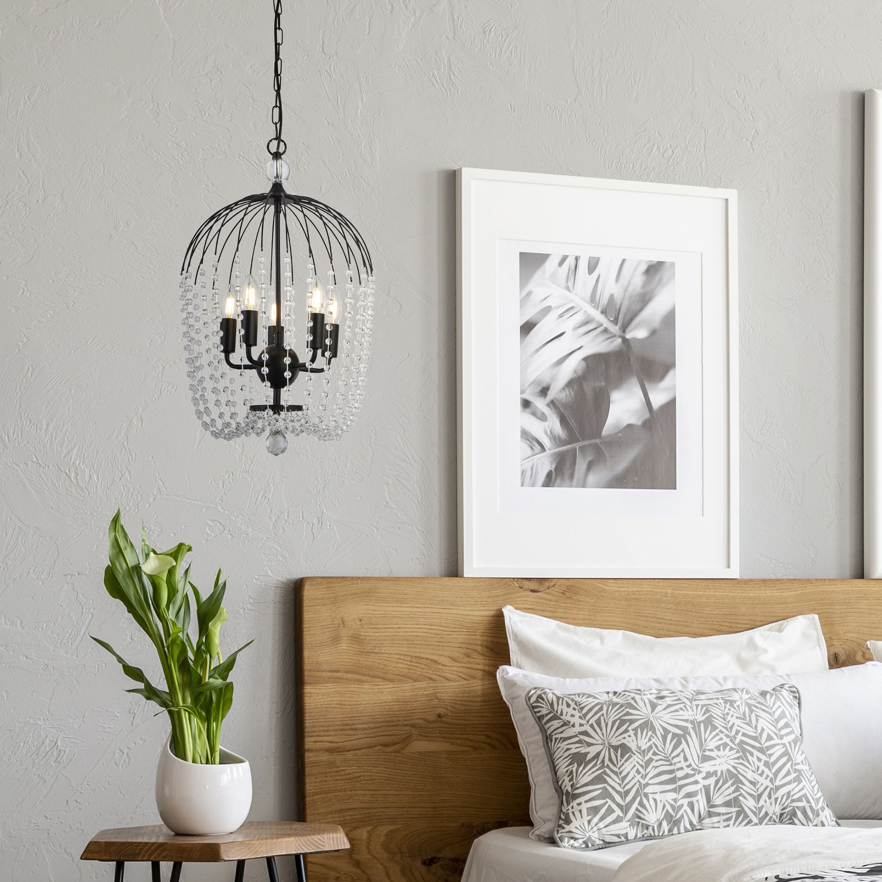 Shower pendant in matt black hanging beside a bed in a bedroom with a wood headboard