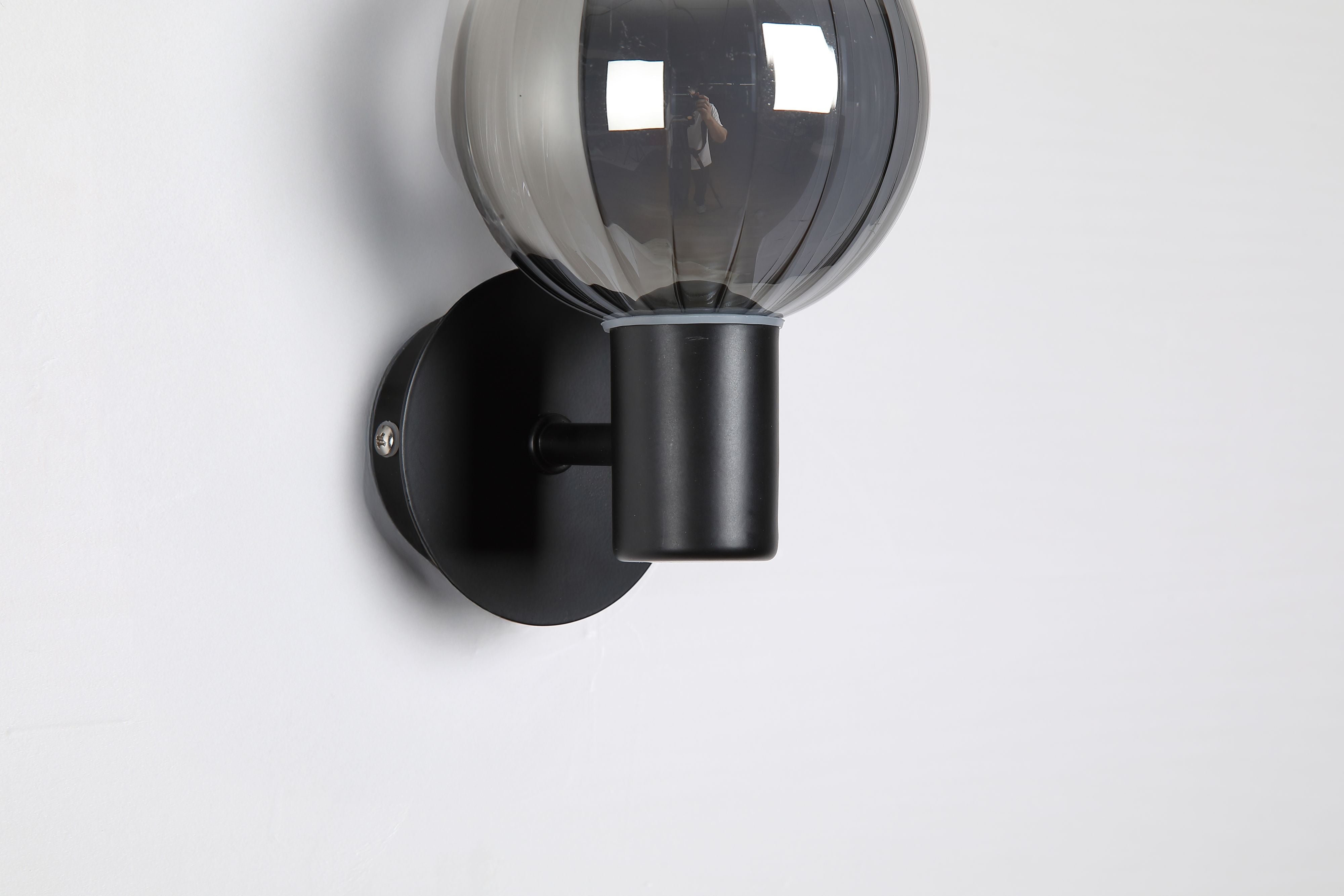 Close up of the Luminsphere's smoked glass sphere and matte black wall mount, unlit