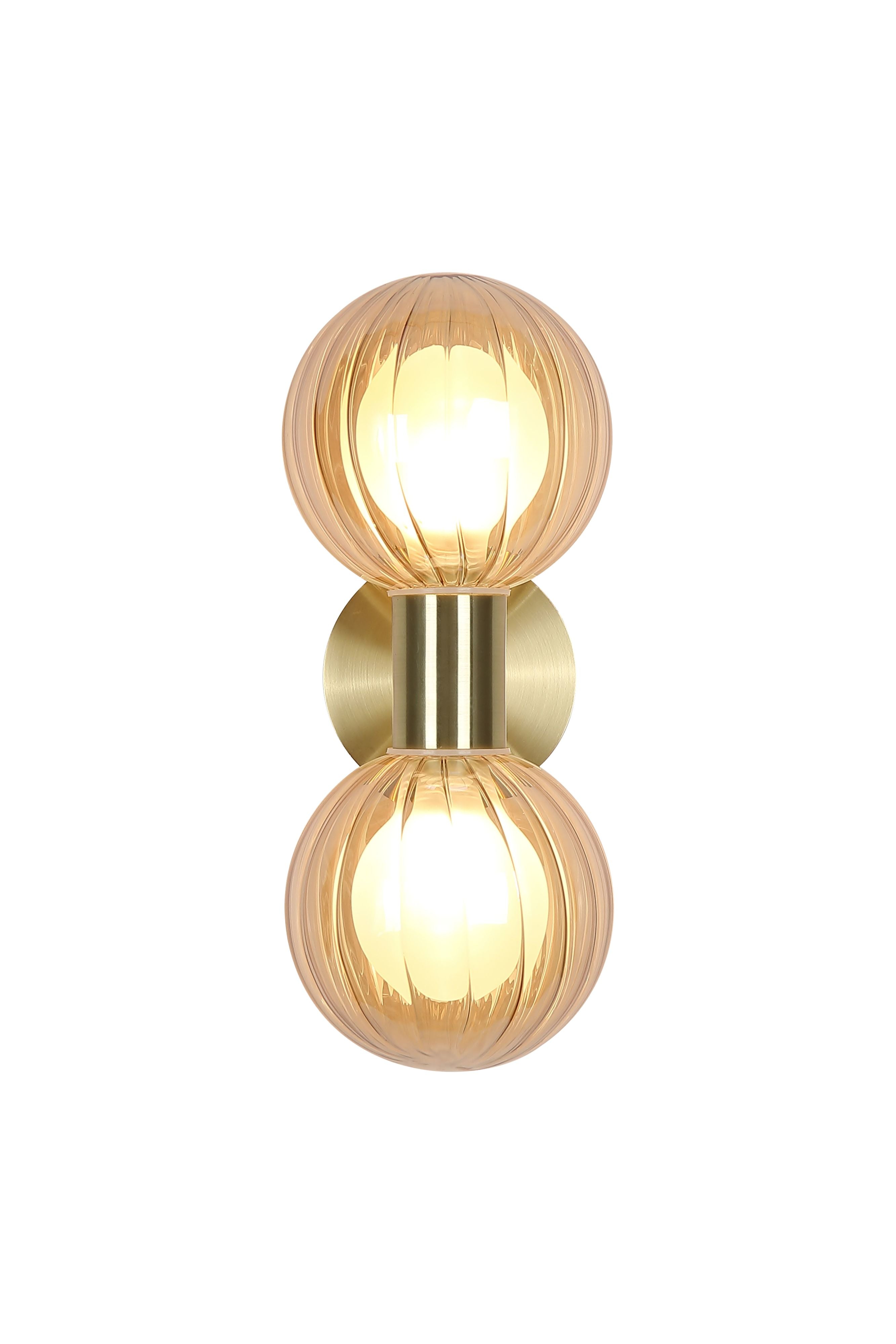 Searchlight Luminsphere 2 Light Wall Light in brushed brass with two ribbed champagne glass globes, lit, angled studio shot