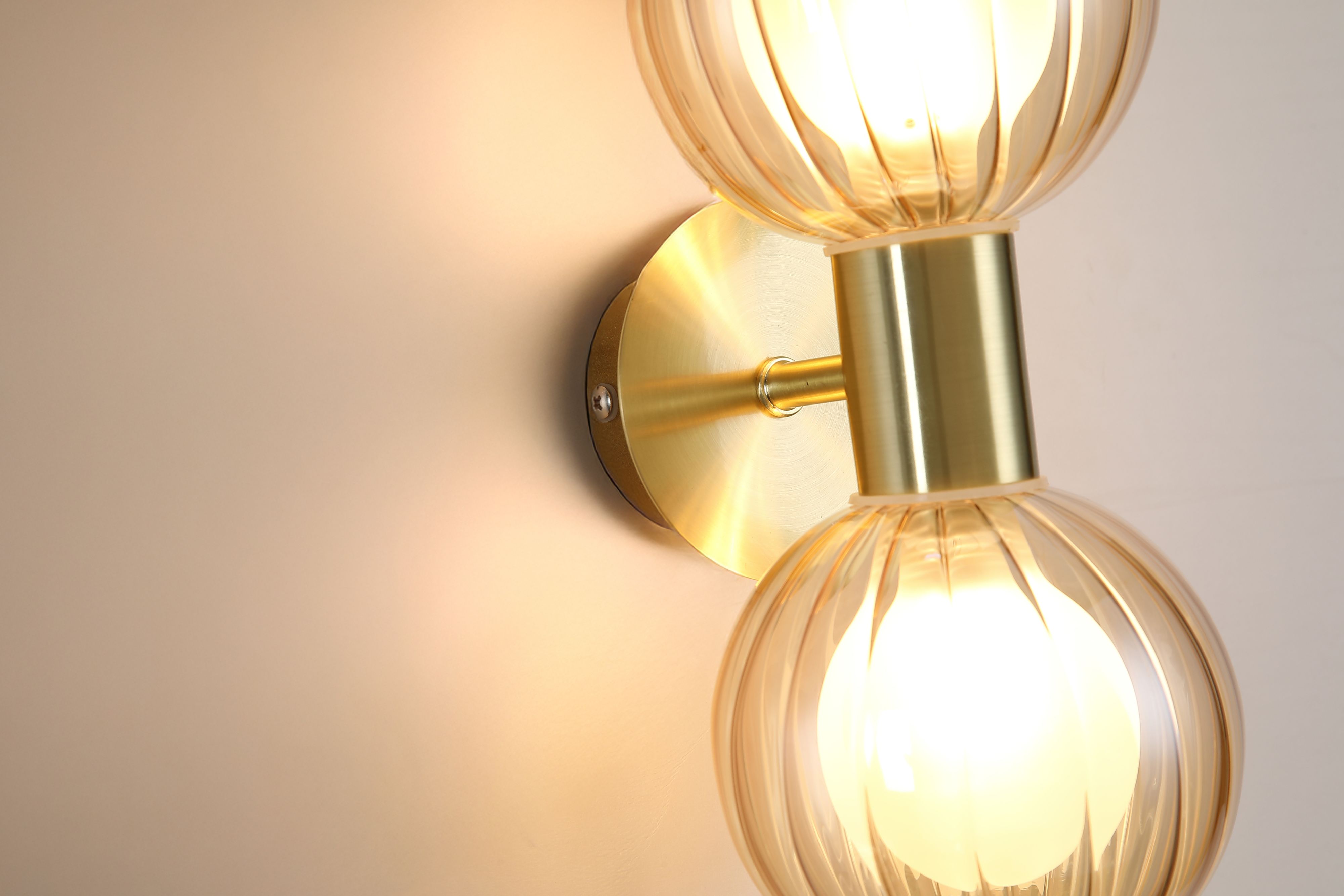 Close up of the ribbed champagne glass globes and brushed brass centre bracket on the Searchlight Luminsphere 2 Light Wall Light
