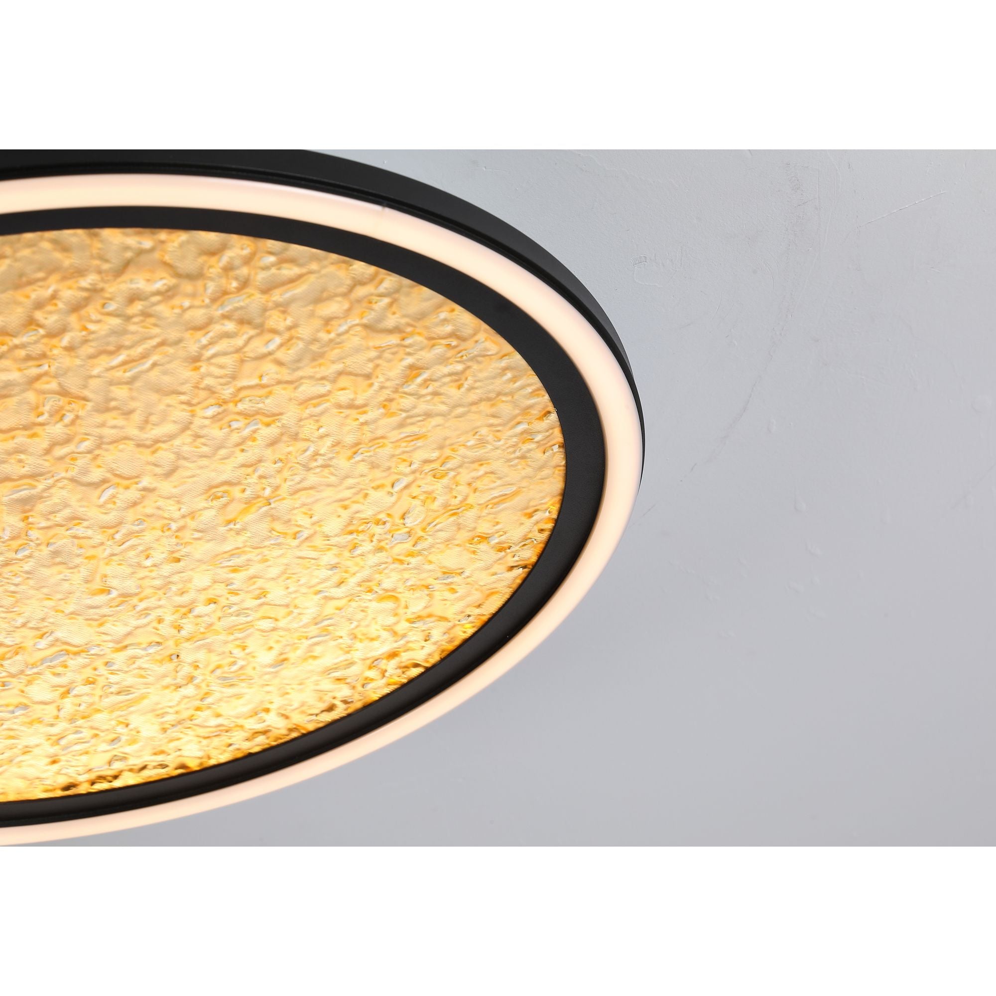 Close up of the Searchlight Luna diffuser edge, showing the textured gold surface and matte black trim against a wall and ceiling