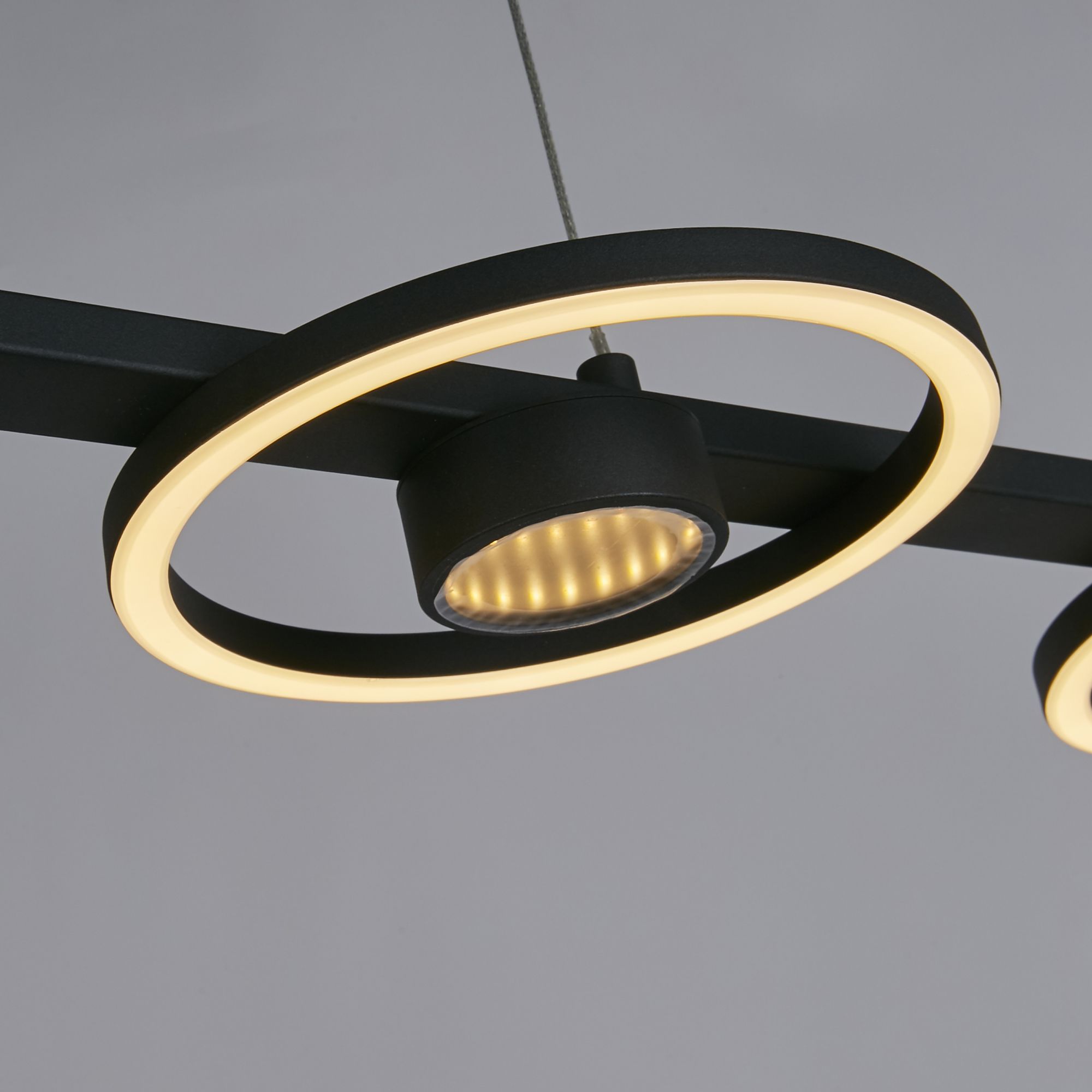 Close up of one ring on the Searchlight Space pendant, showing the black metal ring and integrated LED lit warm white