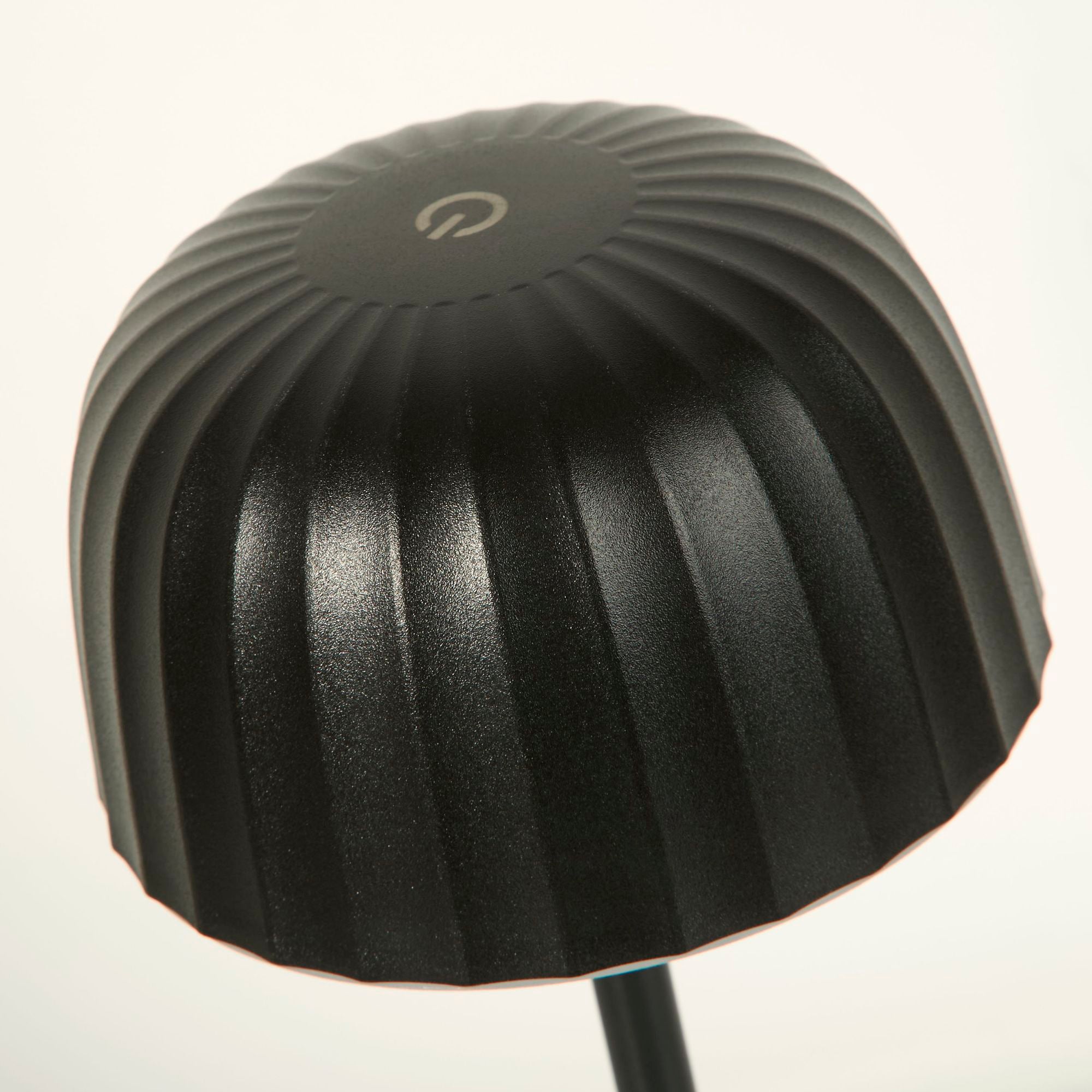 Close up looking down on the black ribbed dome shade of the Ezra table lamp, showing the touch power control icon