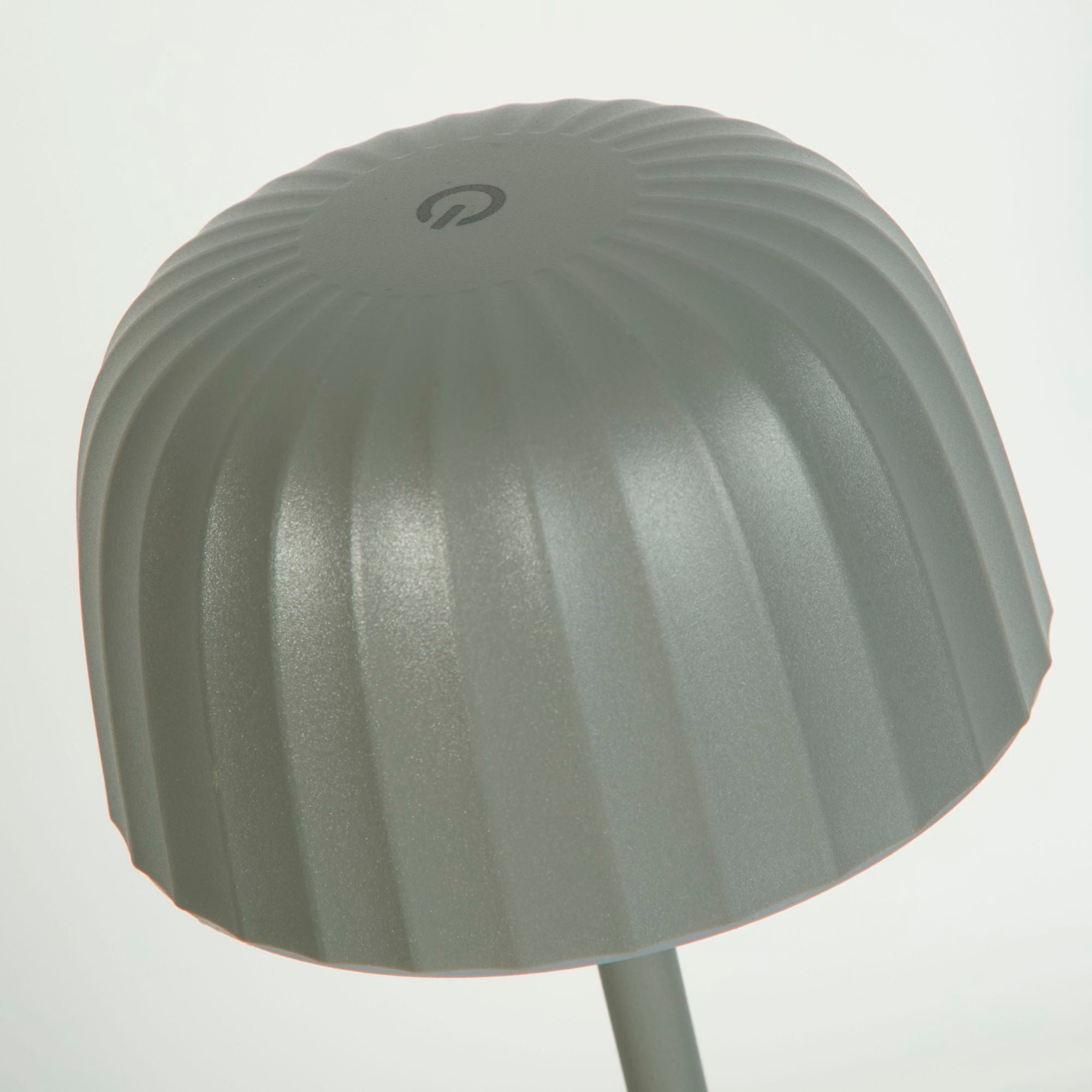 Close up looking down on the grey ribbed dome shade of the Ezra table lamp, showing the touch power control icon