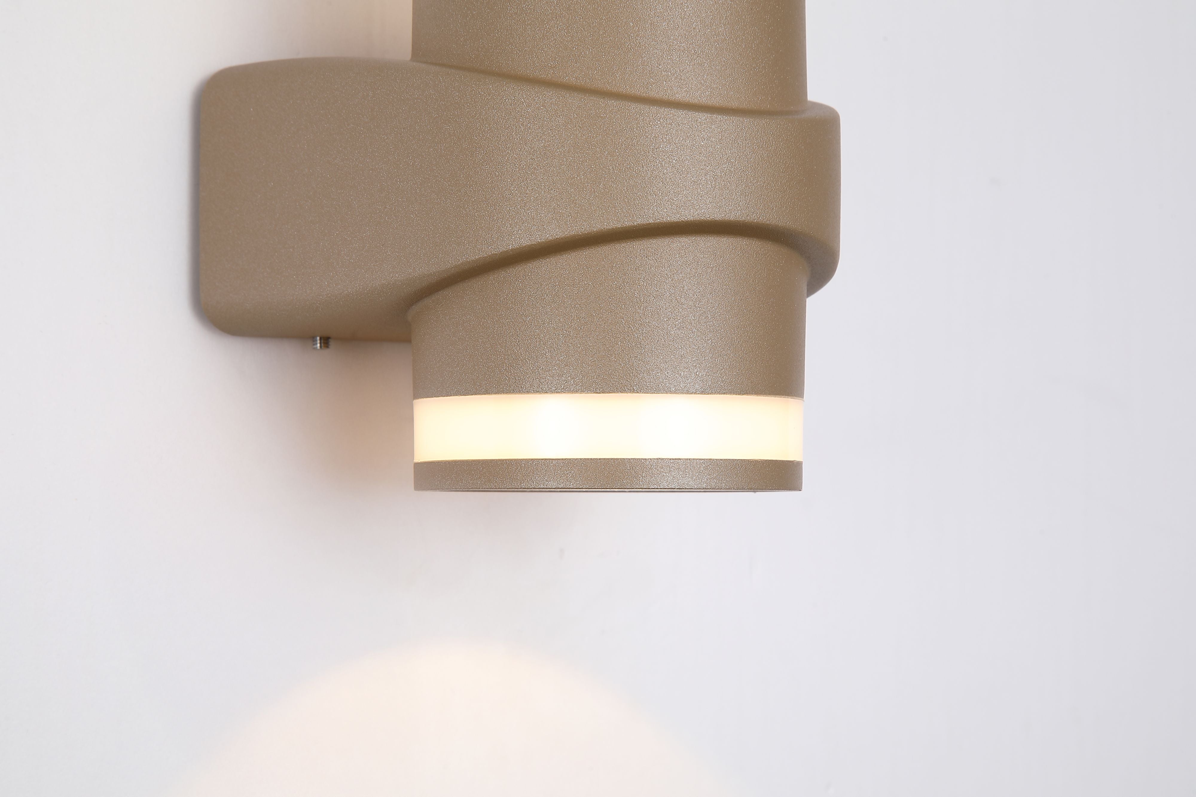Close up of the lower half of the Grip LED outdoor wall light mounted on a white wall, showing the lit bottom light band and central mounting plate