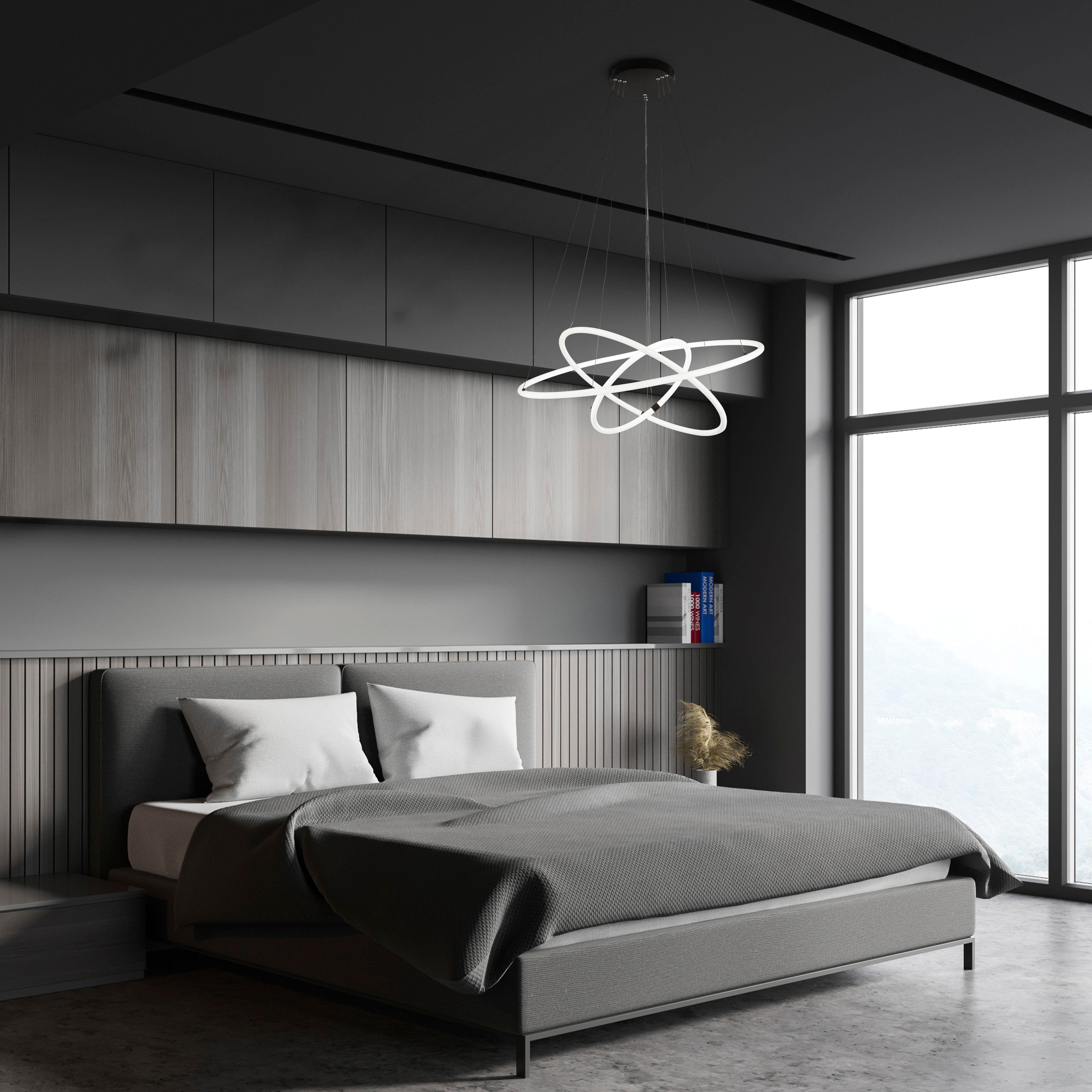 Searchlight Revolve 3 light ring pendant styled at an angle above a bed, in a dark grey bedroom with panelled walls