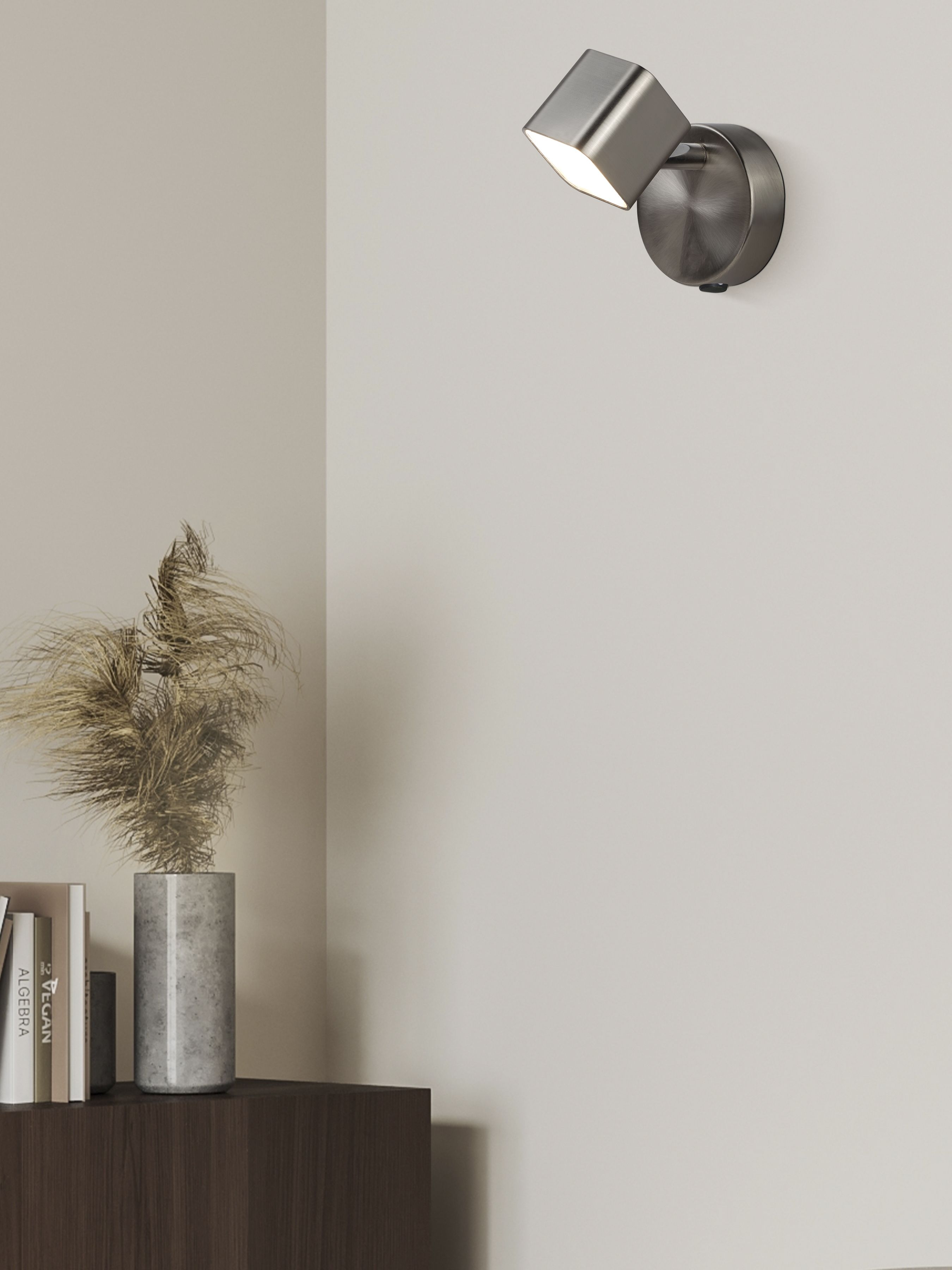 Searchlight Quad Spotlight Wall Light in satin silver mounted on a beige wall above a console styled with books and dried grasses