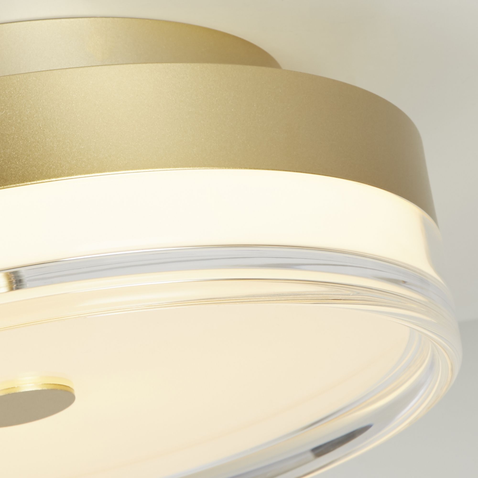 Close up of the Searchlight Cyprus's gold band and clear acrylic rim, showing the warm glow at the shade edge