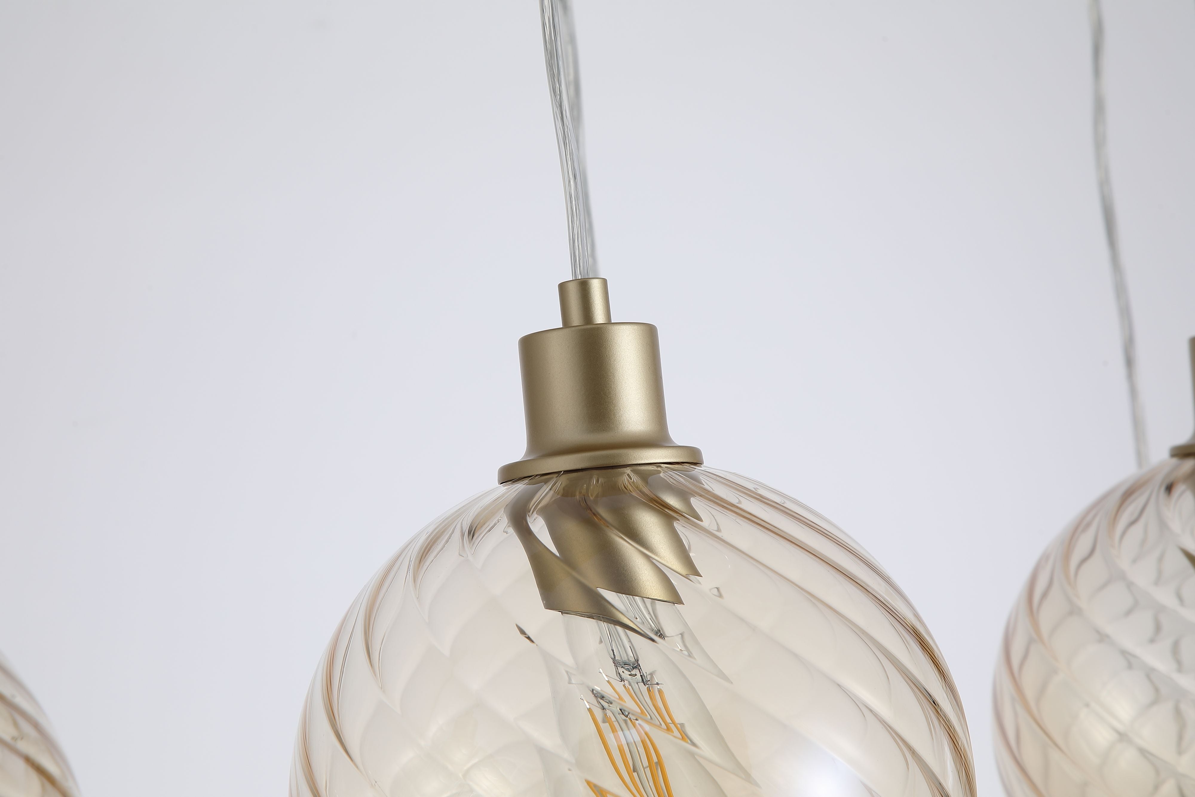 Close up of the gold lamp holder and swirled champagne glass texture on the Searchlight Radiance Bar Pendant globe shades