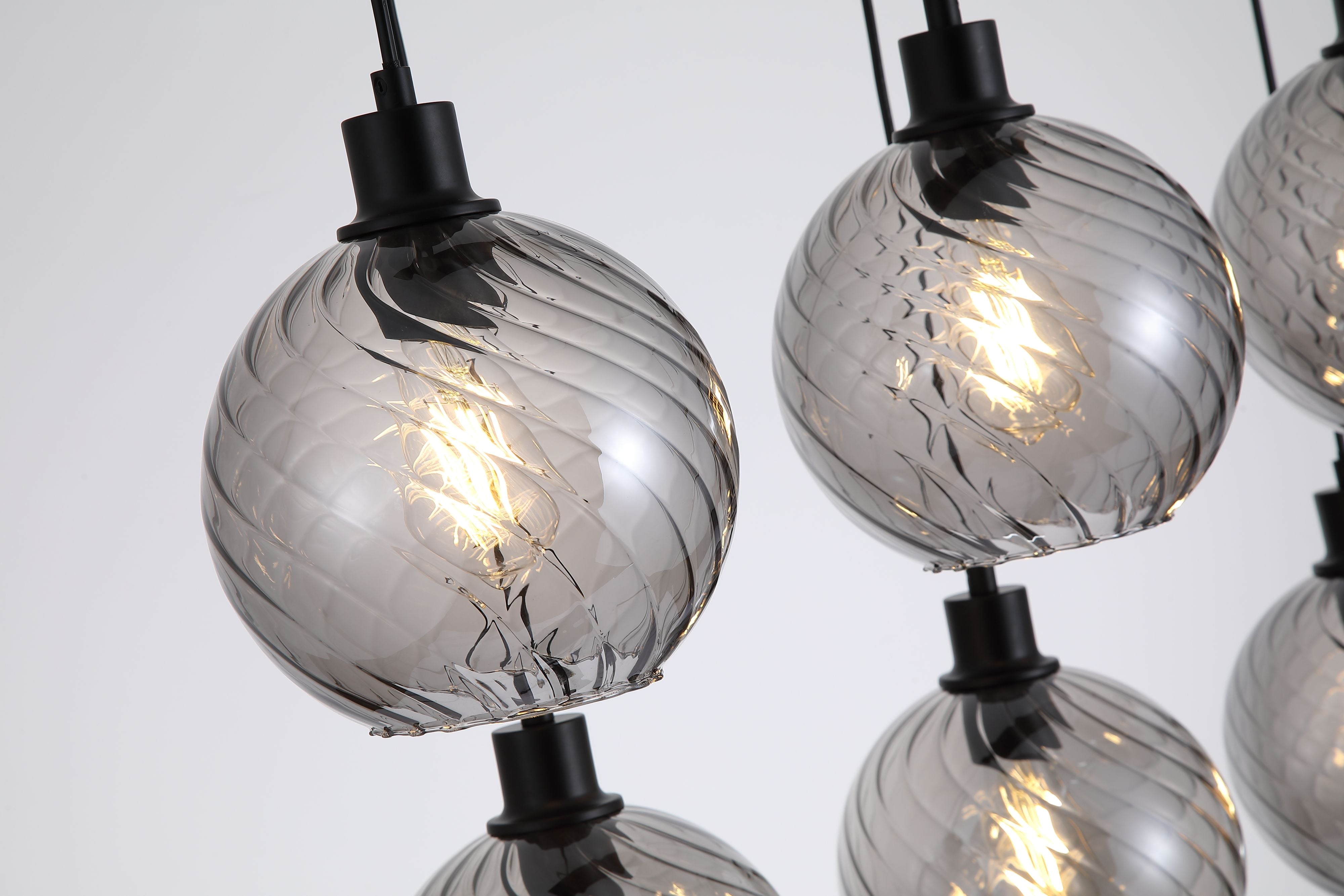 Close up of two smoked glass globe shades on the Radiance 6 Light Bar Pendant, showing the swirled texture and matte black lamp holders