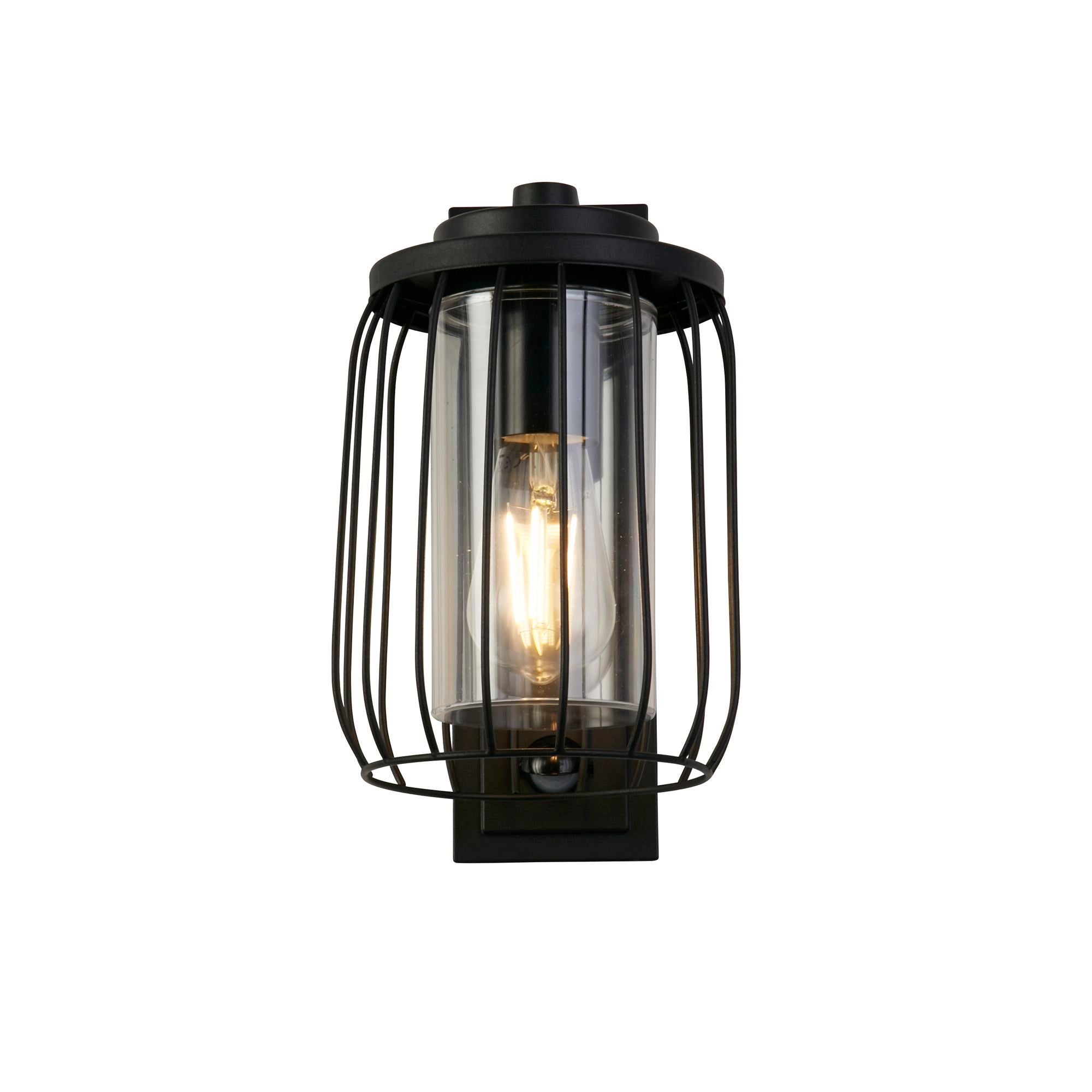 Reed 1 Light Wall Light with PIR in black, front view of the wire cage shade and clear polycarbonate diffuser with a warm lit filament style bulb inside.