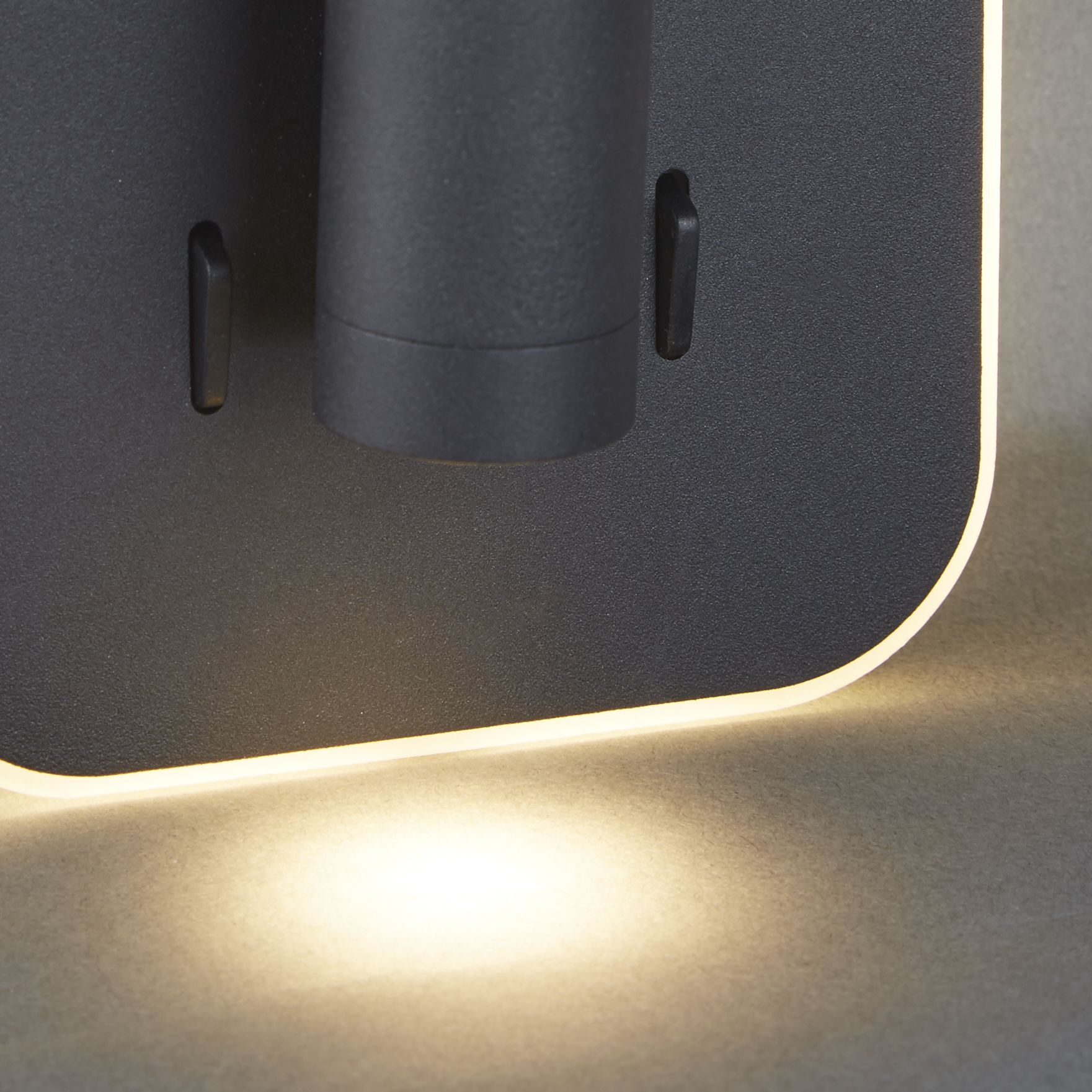 Close up of the acrylic edge trim glow and rocker switches on the Sonny LED wall light in black