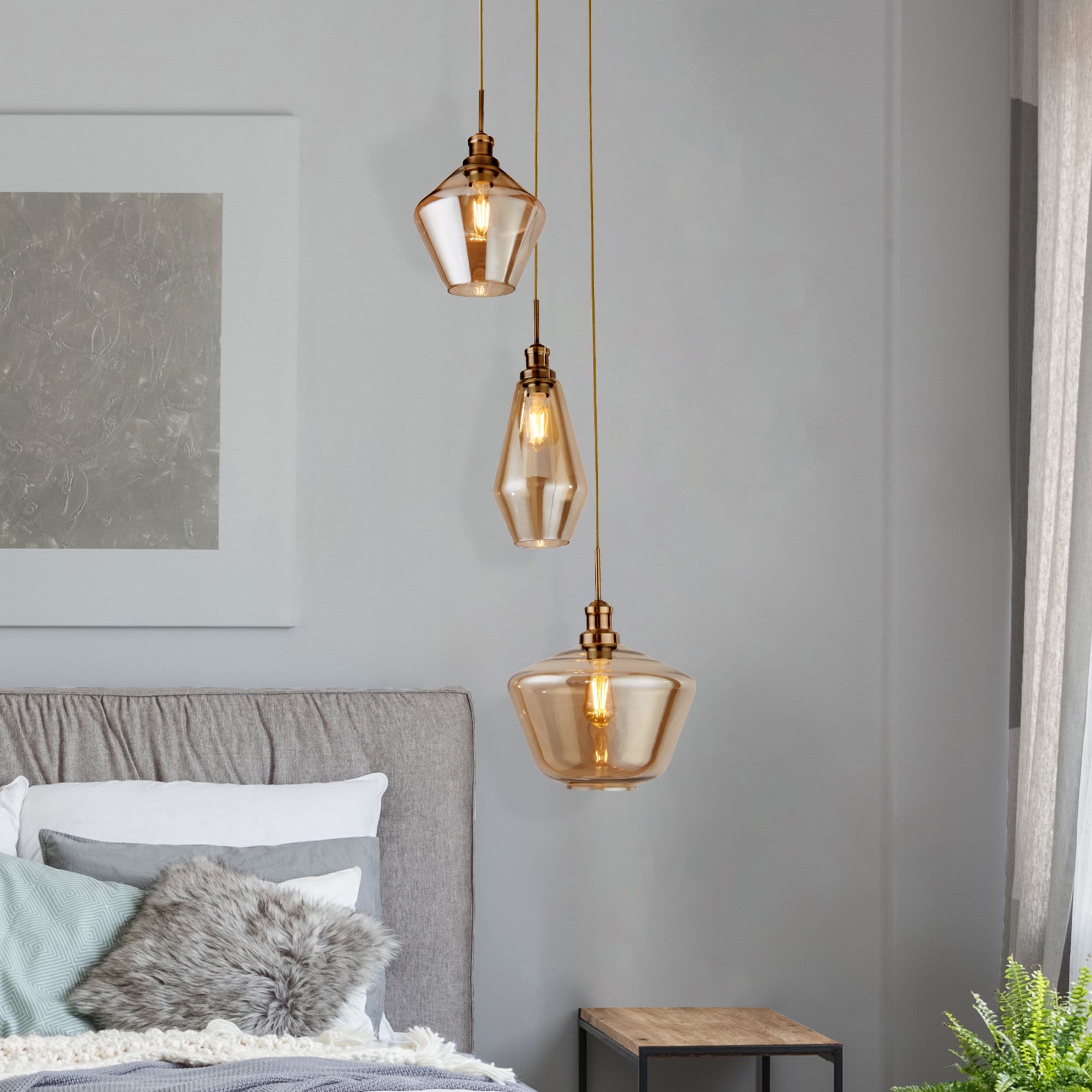 Searchlight Mia 3 light multi drop pendant in antique brass and amber glass styled above a bedside table in a grey bedroom