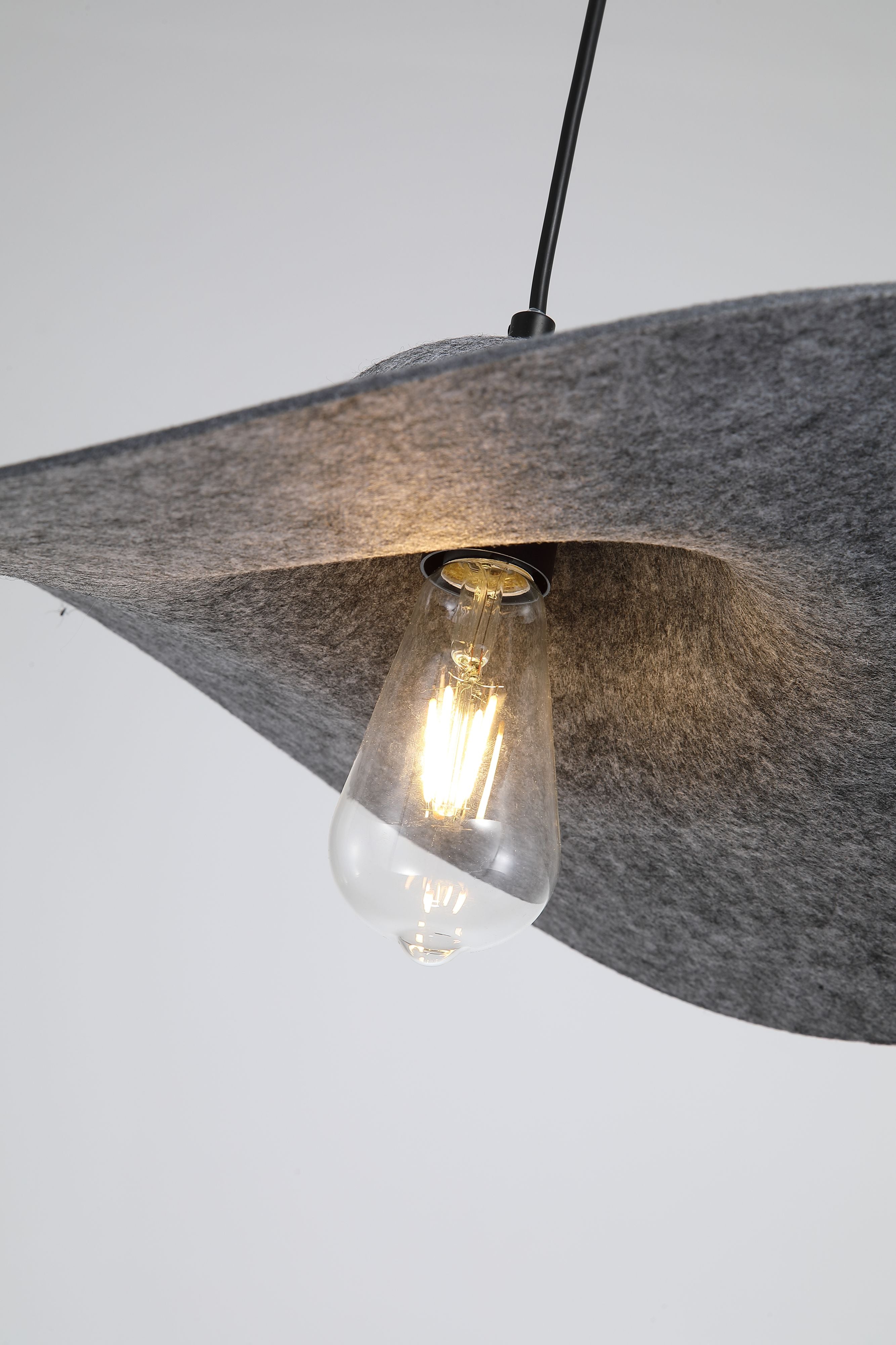 Close up of the Ripple pendant's black felt brim with the exposed LED filament bulb glowing underneath